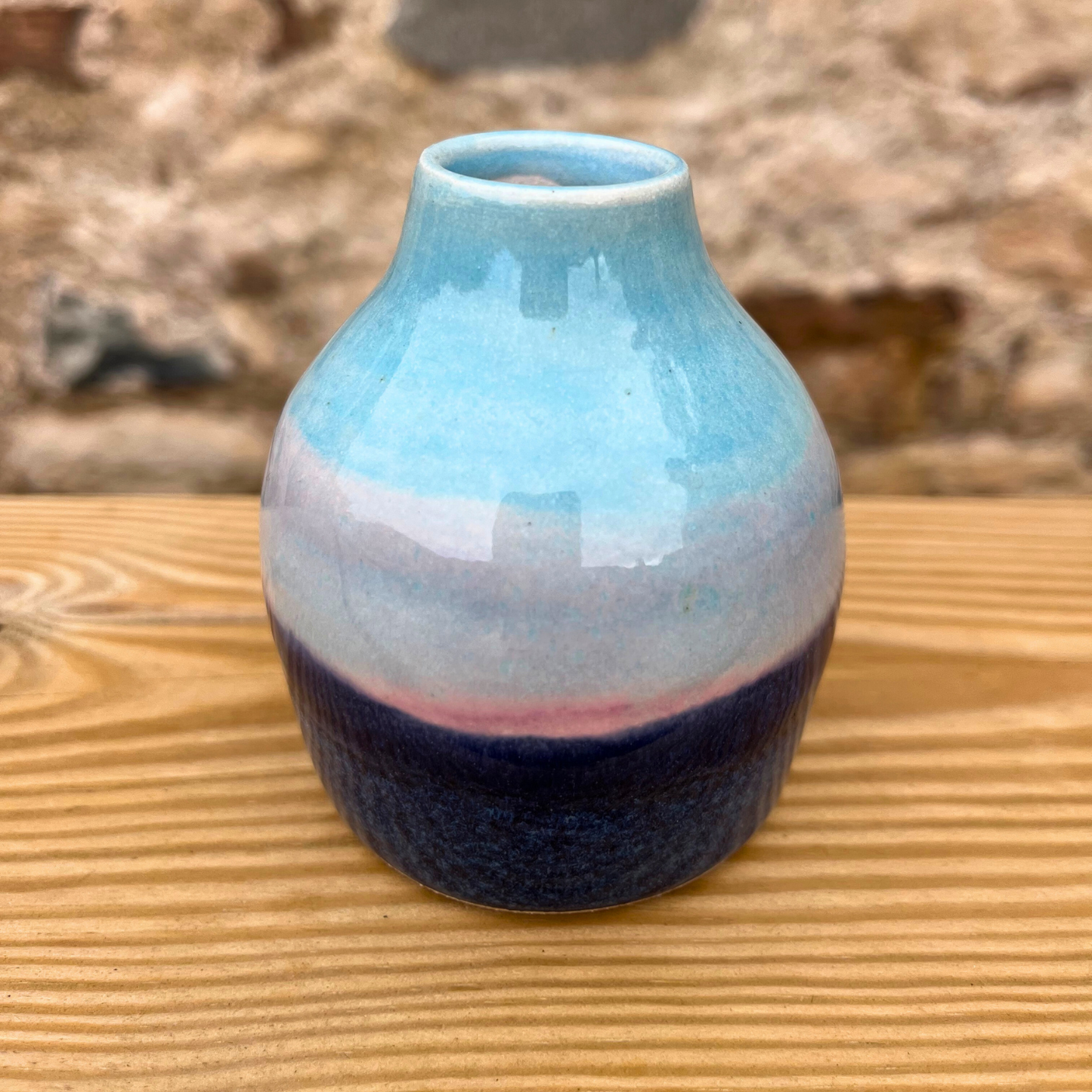 Ceramic vase with blue and purple gradient on a wooden surface