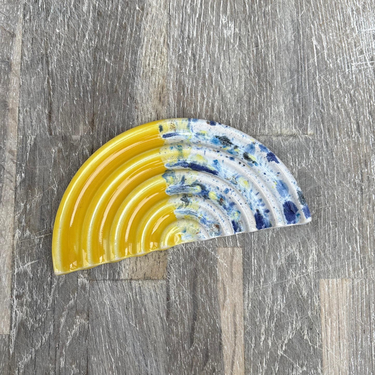 Decorative soap dish with yellow and blue patterns on a wooden surface