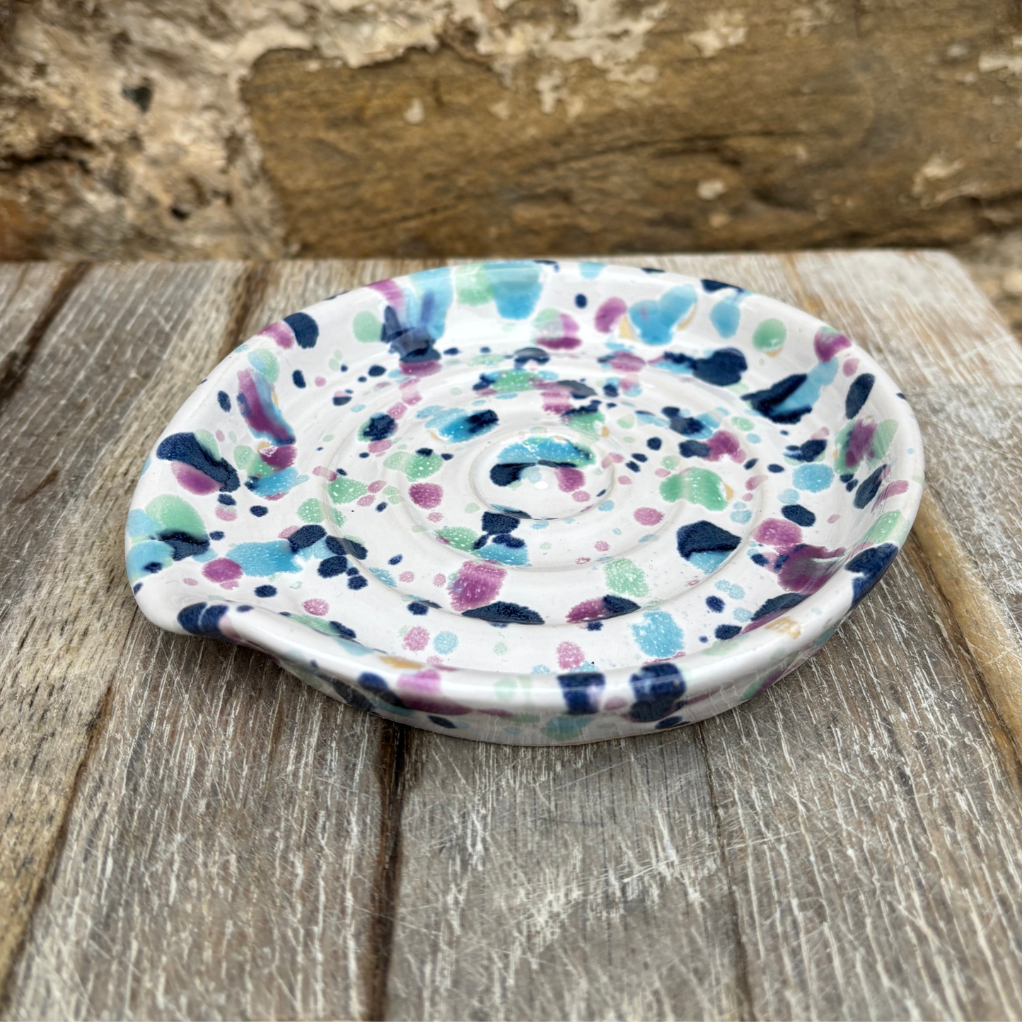 Multicolored speckled ceramic dish on a wooden surface