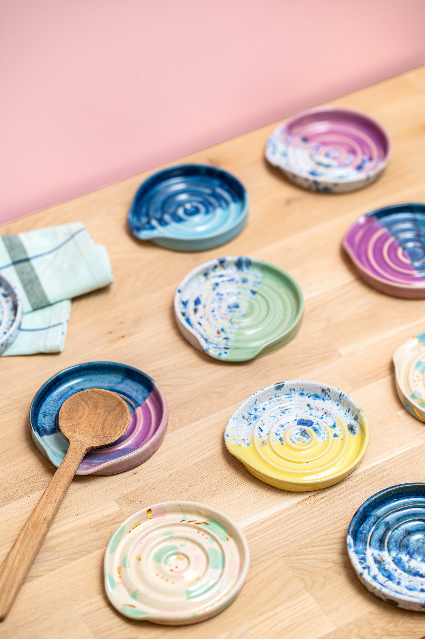Colorful ceramic plates on a wooden surface with a pink background