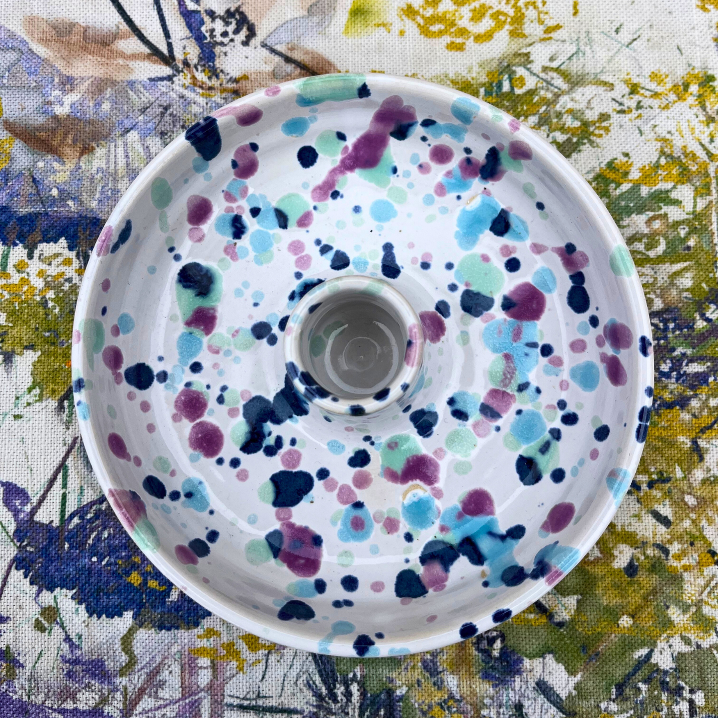 Decorative candlestick holder with colorful polka dot pattern on a floral fabric background