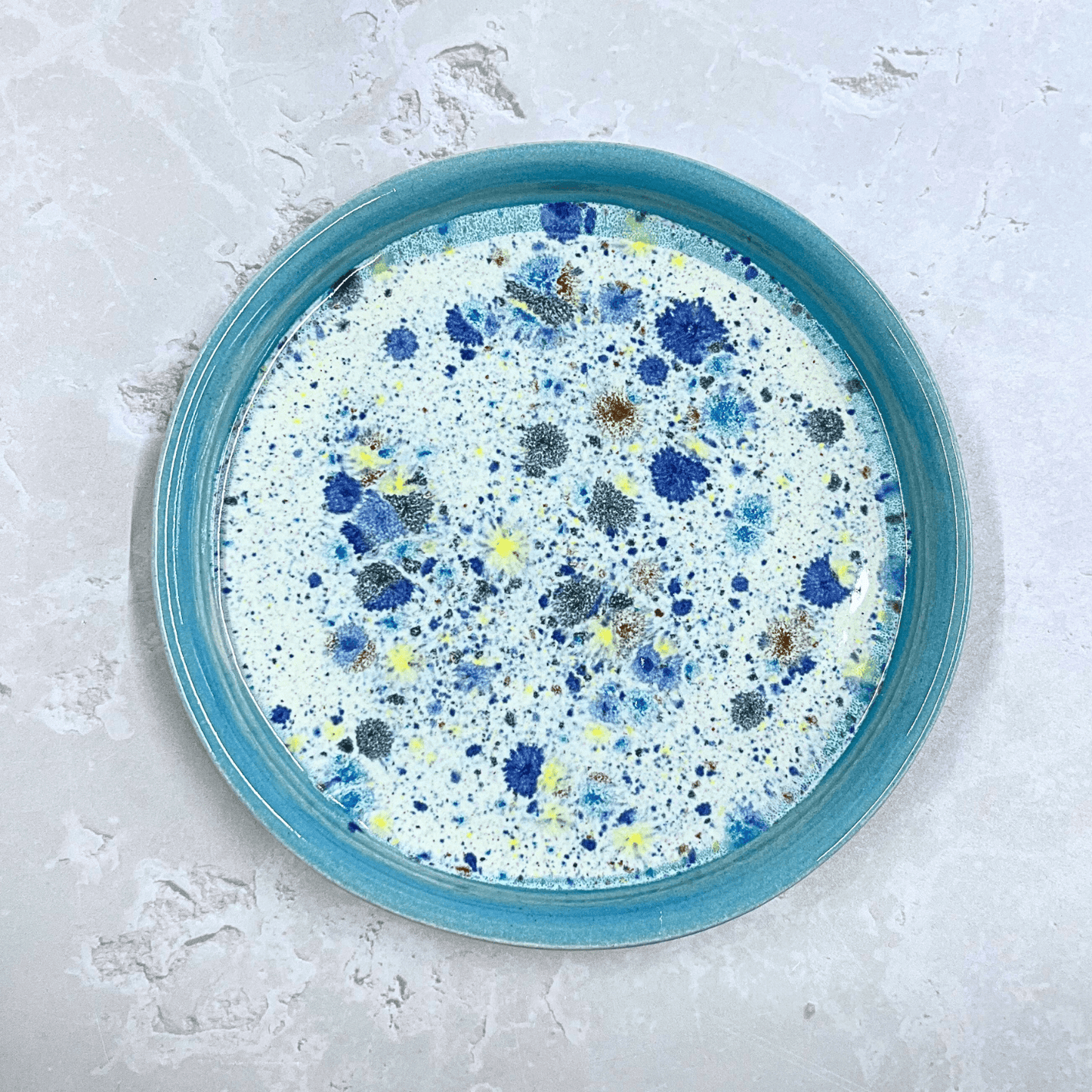 Ella Fletcher Designs Handmade Ceramic Dinner in Pale Blue Shoreline, round plate with pale blue edge, middle multicoloured speckles with white background