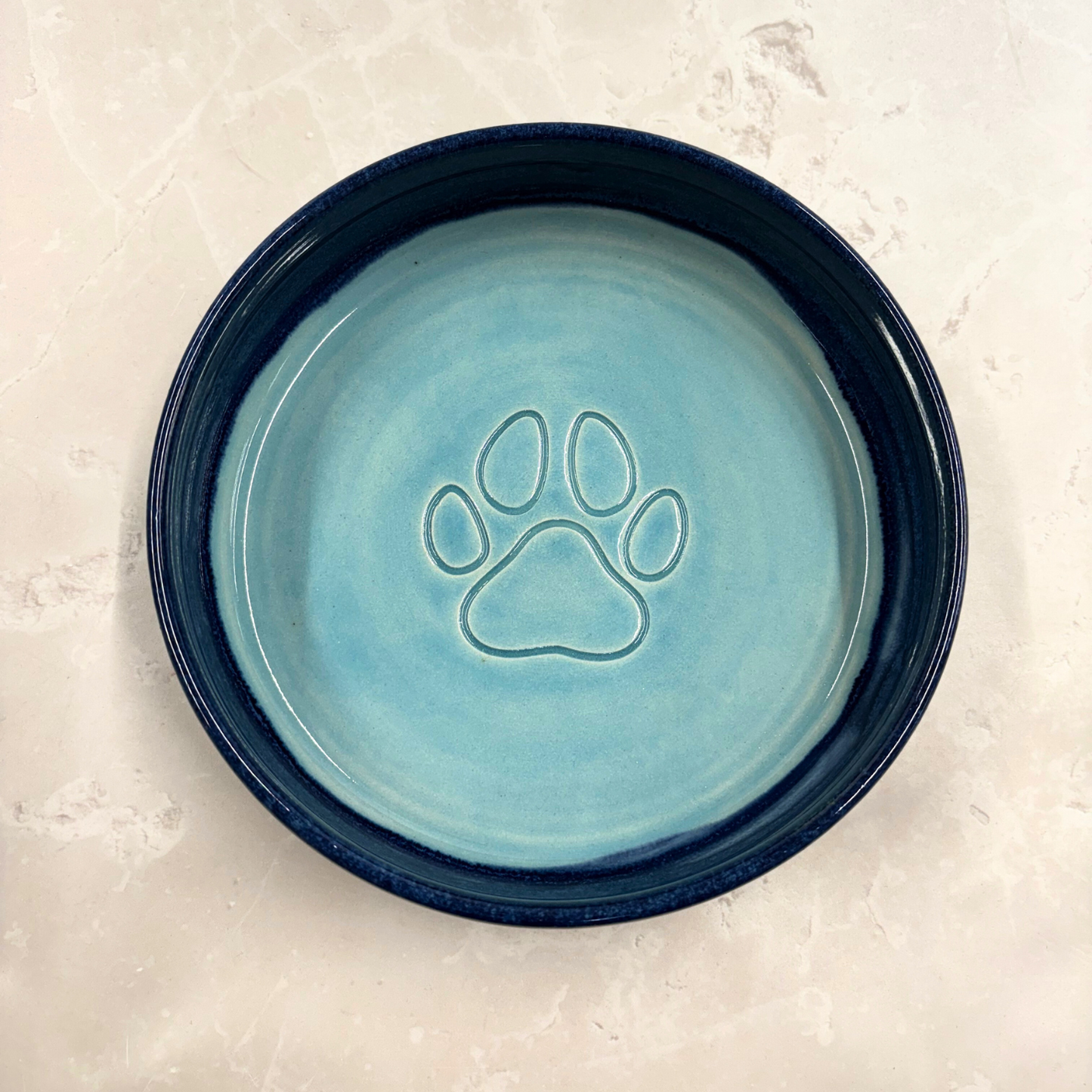 Ella Fletcher Designs handmade Blue ceramic pet bowl with a paw print design on a light gray background