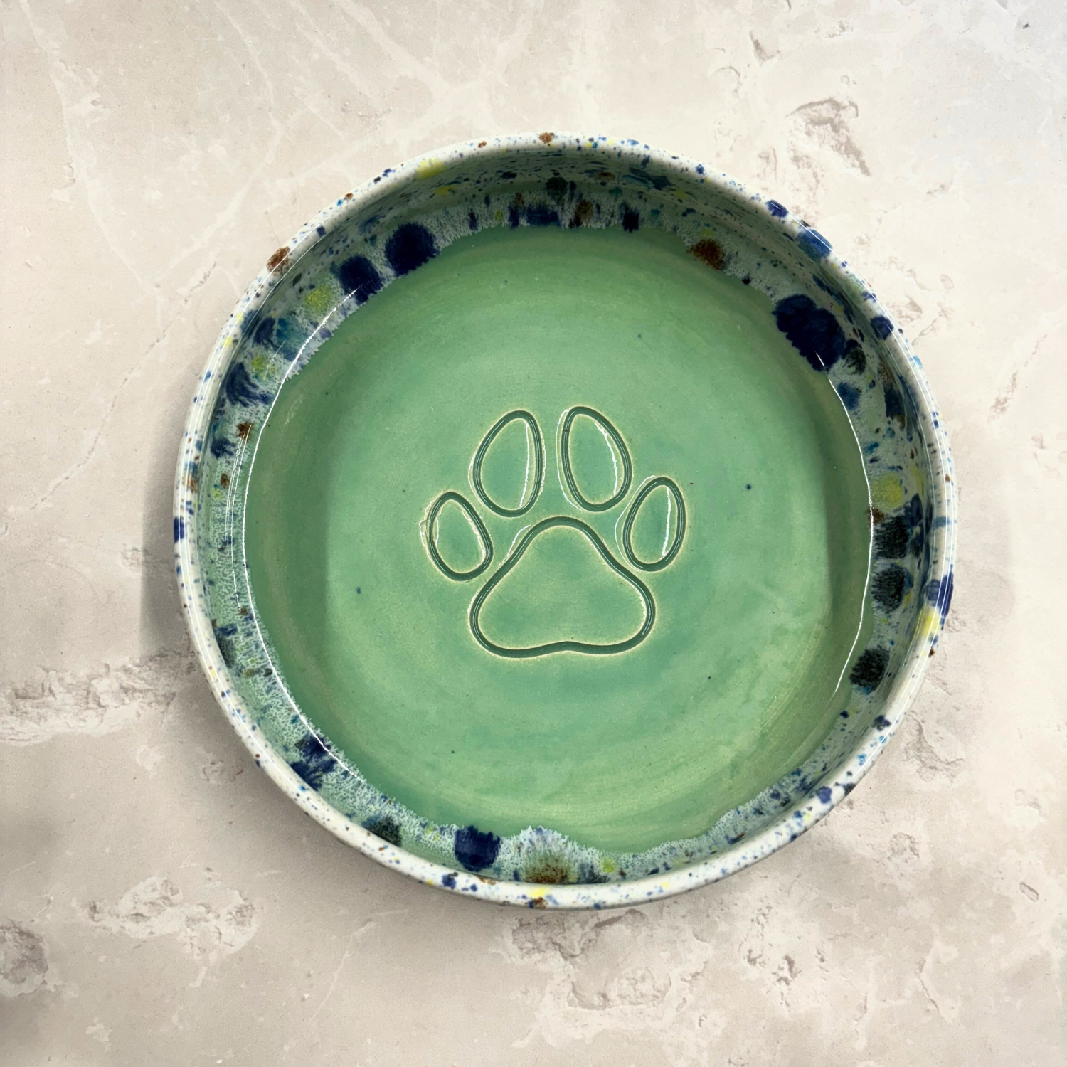 Ella Fletcher Designs handmade Green ceramic bowl with a paw print design on a light gray background