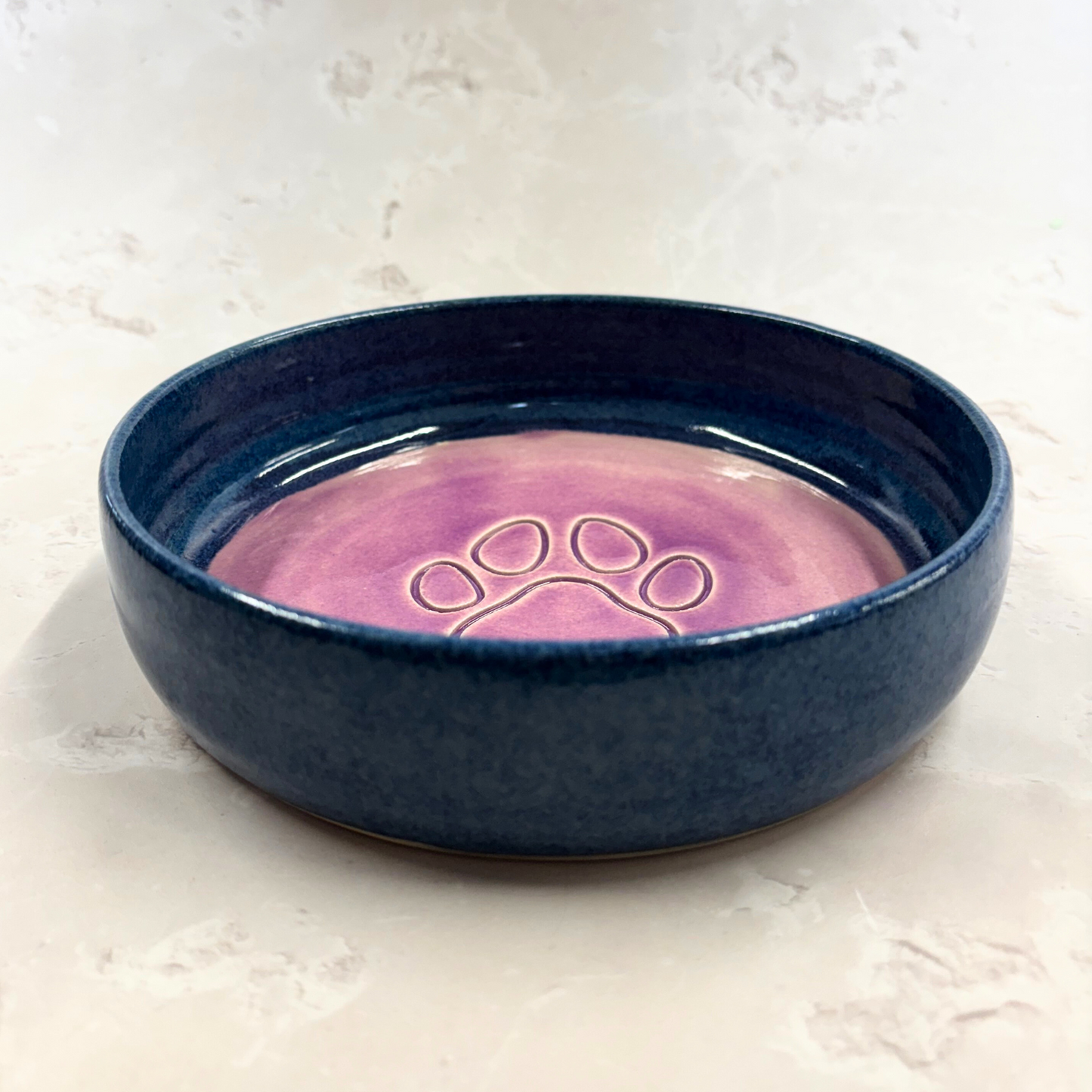 Ella Fletcher Designs handmade Blue ceramic pet bowl with pink interior and paw print design on a light background