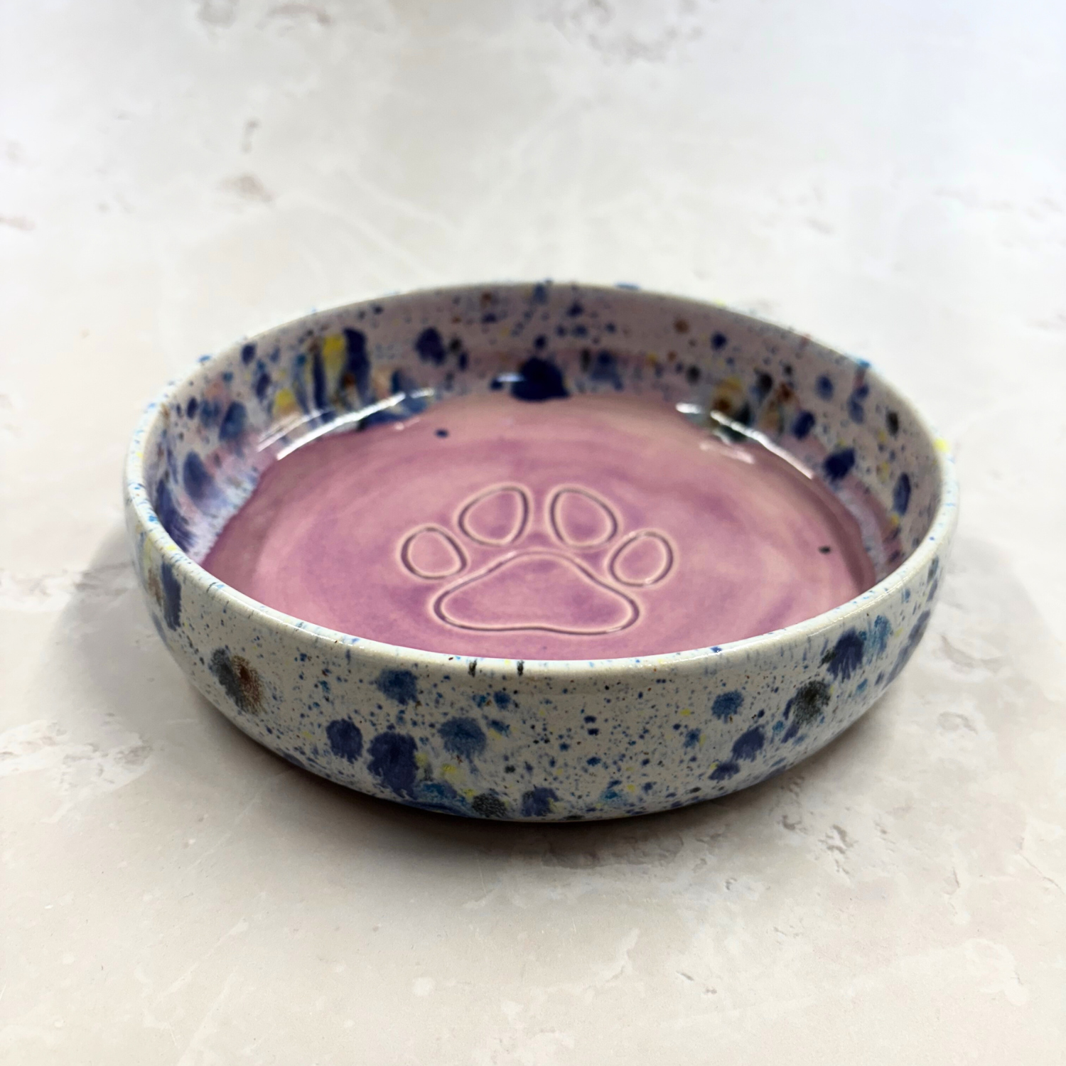 Ella Fletcher Designs handmade Ceramic pet bowl with speckled blue and white design and paw print on a light background