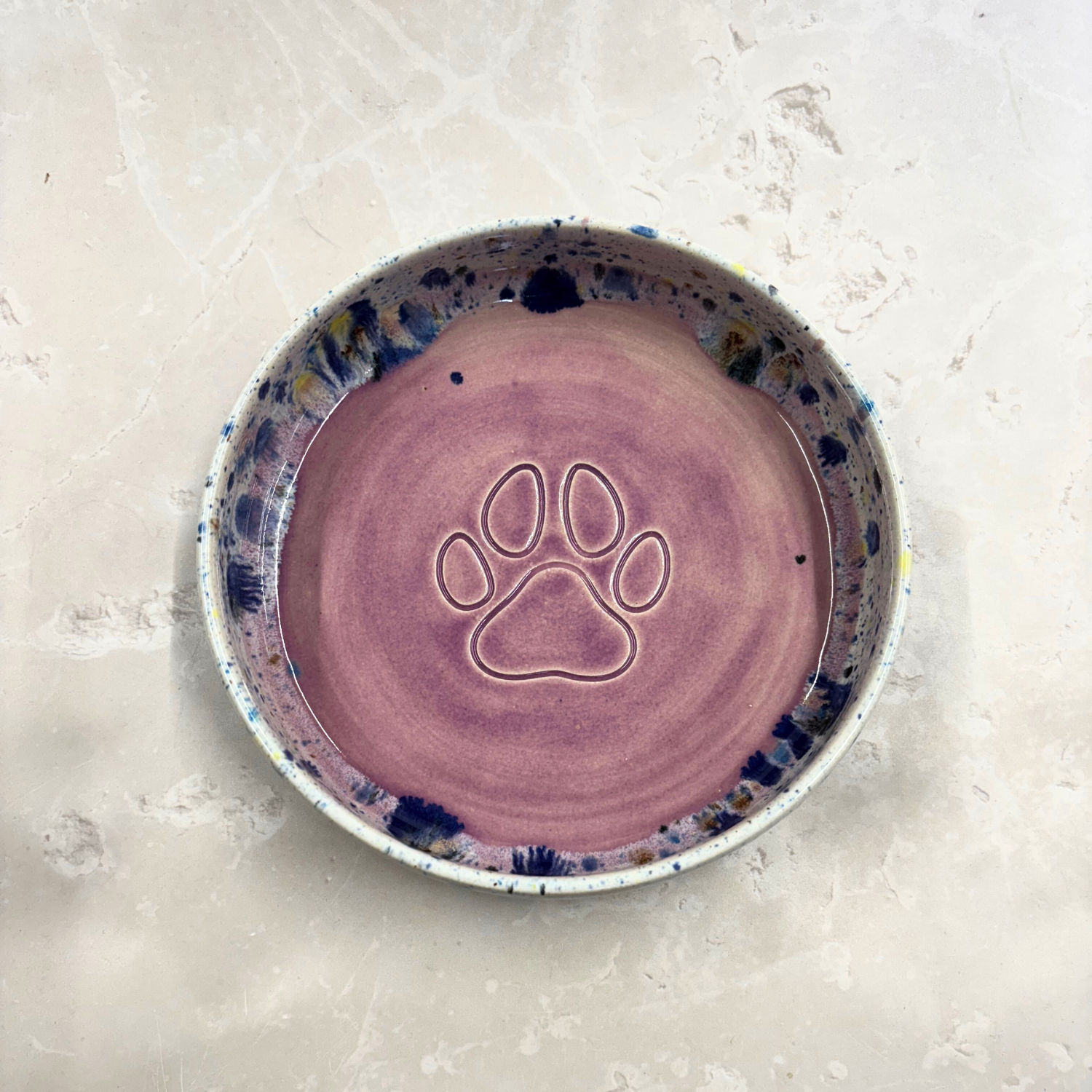 Ella Fletcher Designs handmade Ceramic bowl with a paw print design on a light gray surface