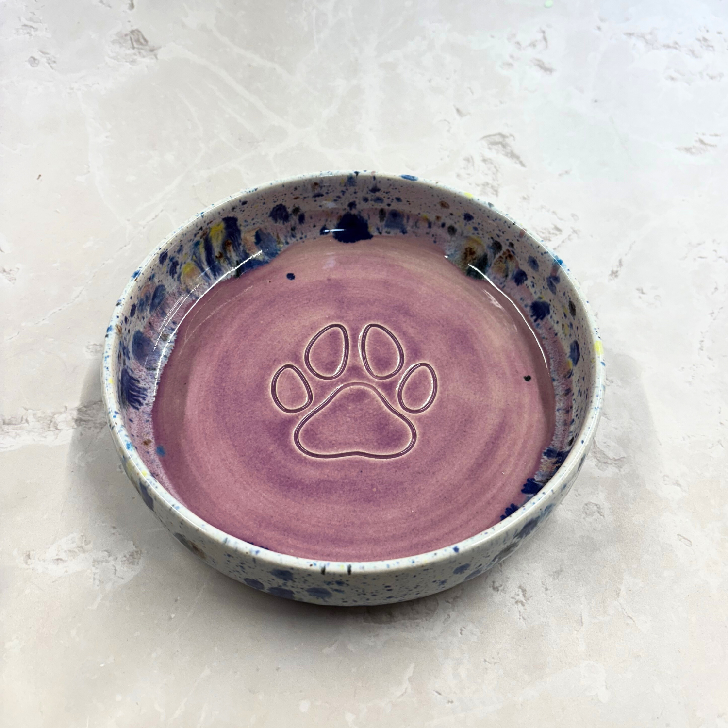 Ella Fletcher Designs handmade  Ceramic pet bowl with purple interior and speckled exterior on a light gray background