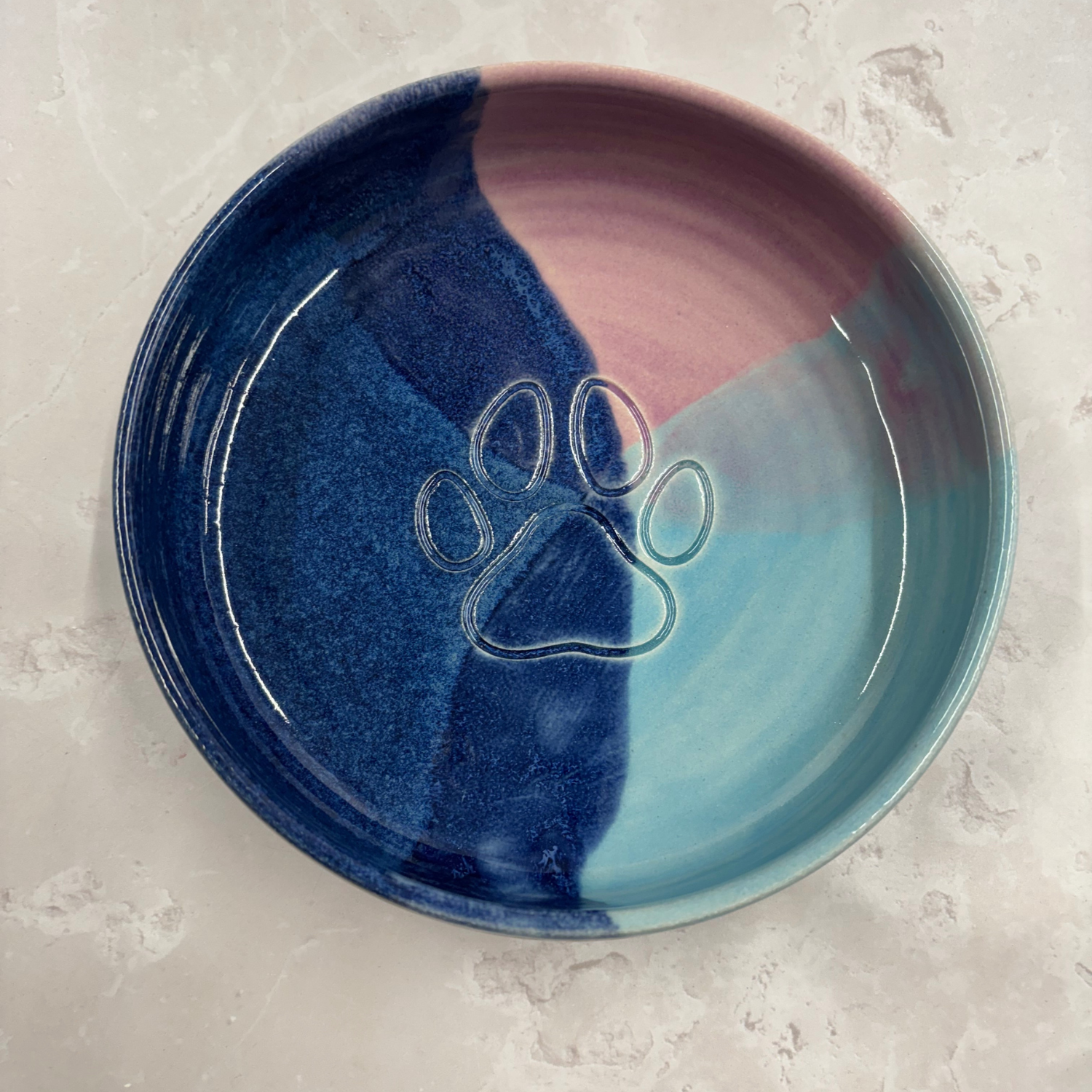 Ella Fletcher Designs handmade Ceramic dish with blue and pink gradient and a paw print design on a light gray surface.