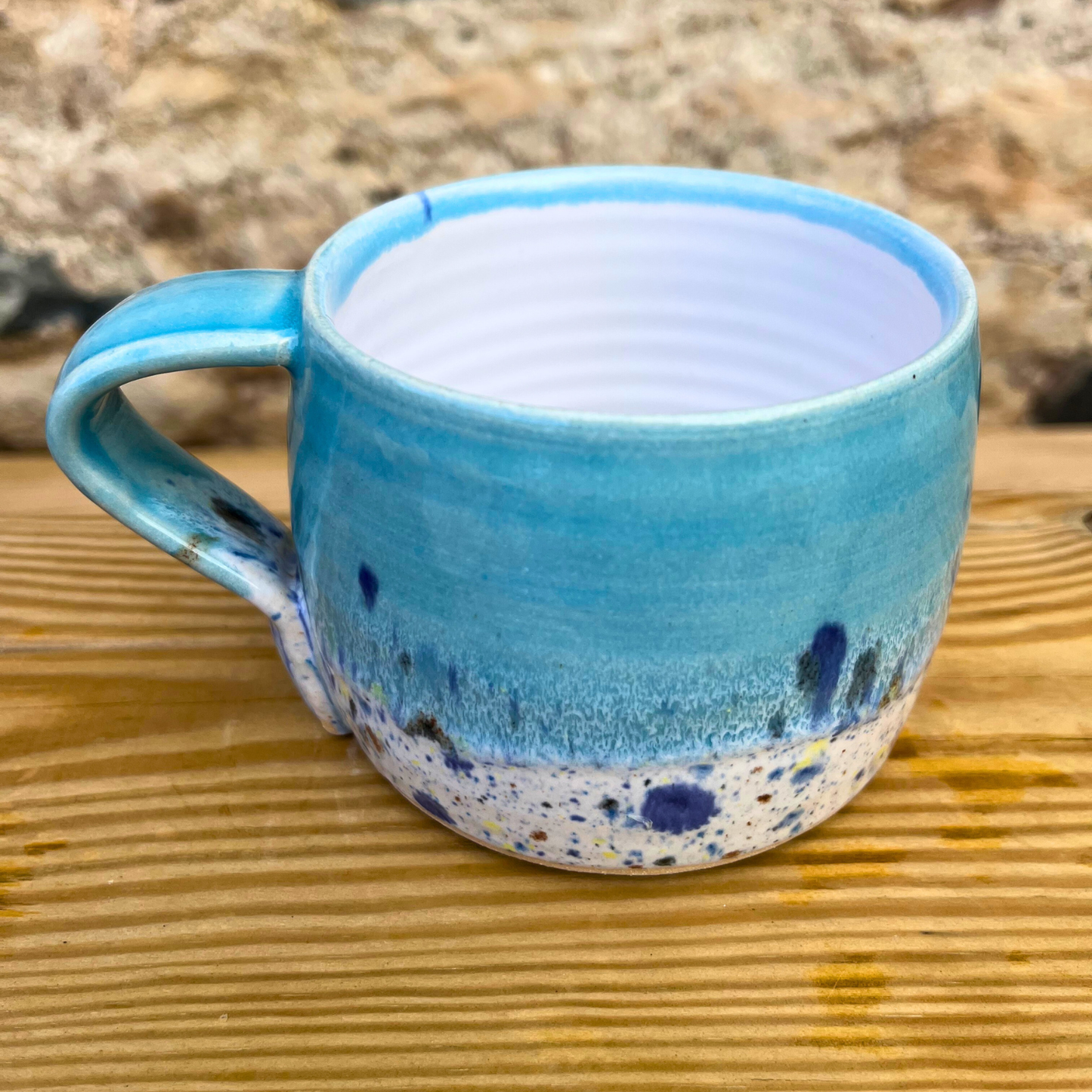 Blue ceramic mug with speckled design on a wooden surface