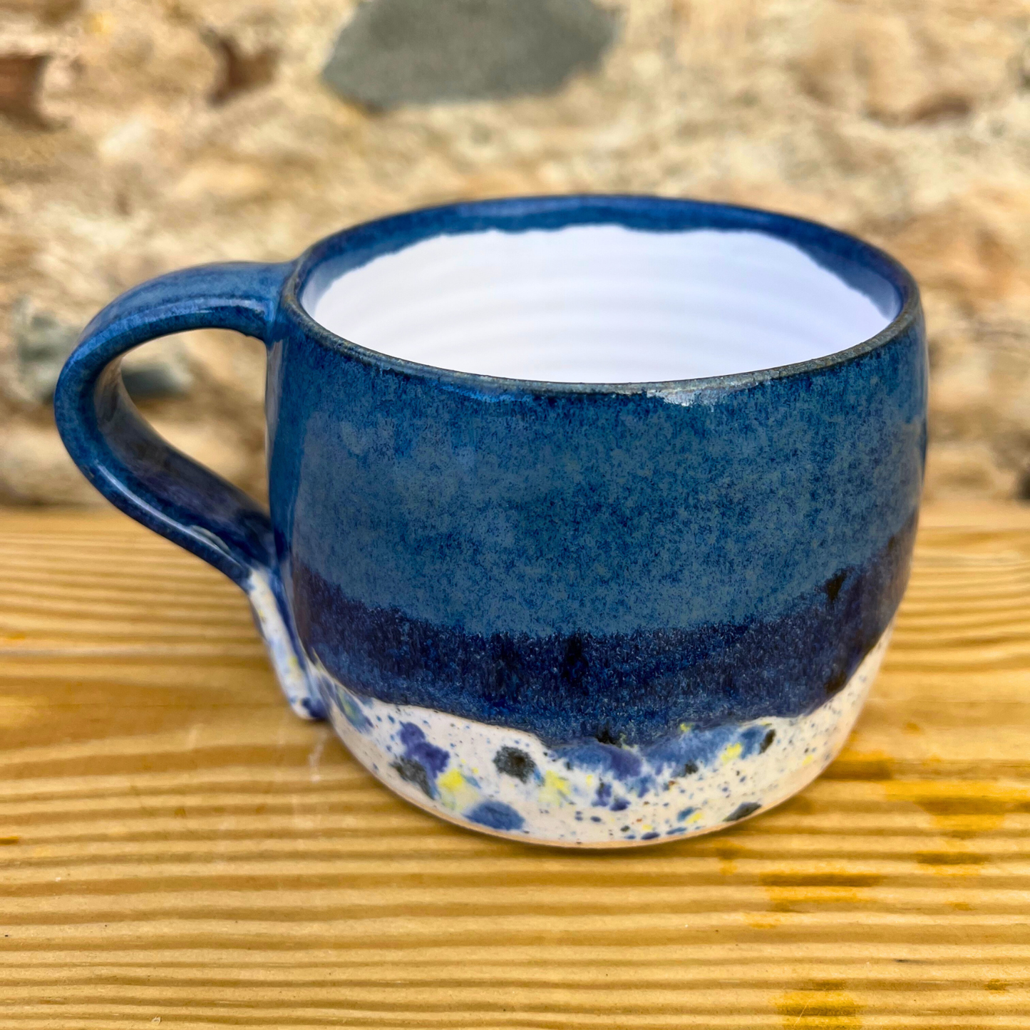 Blue ceramic mug with speckled design on a wooden surface