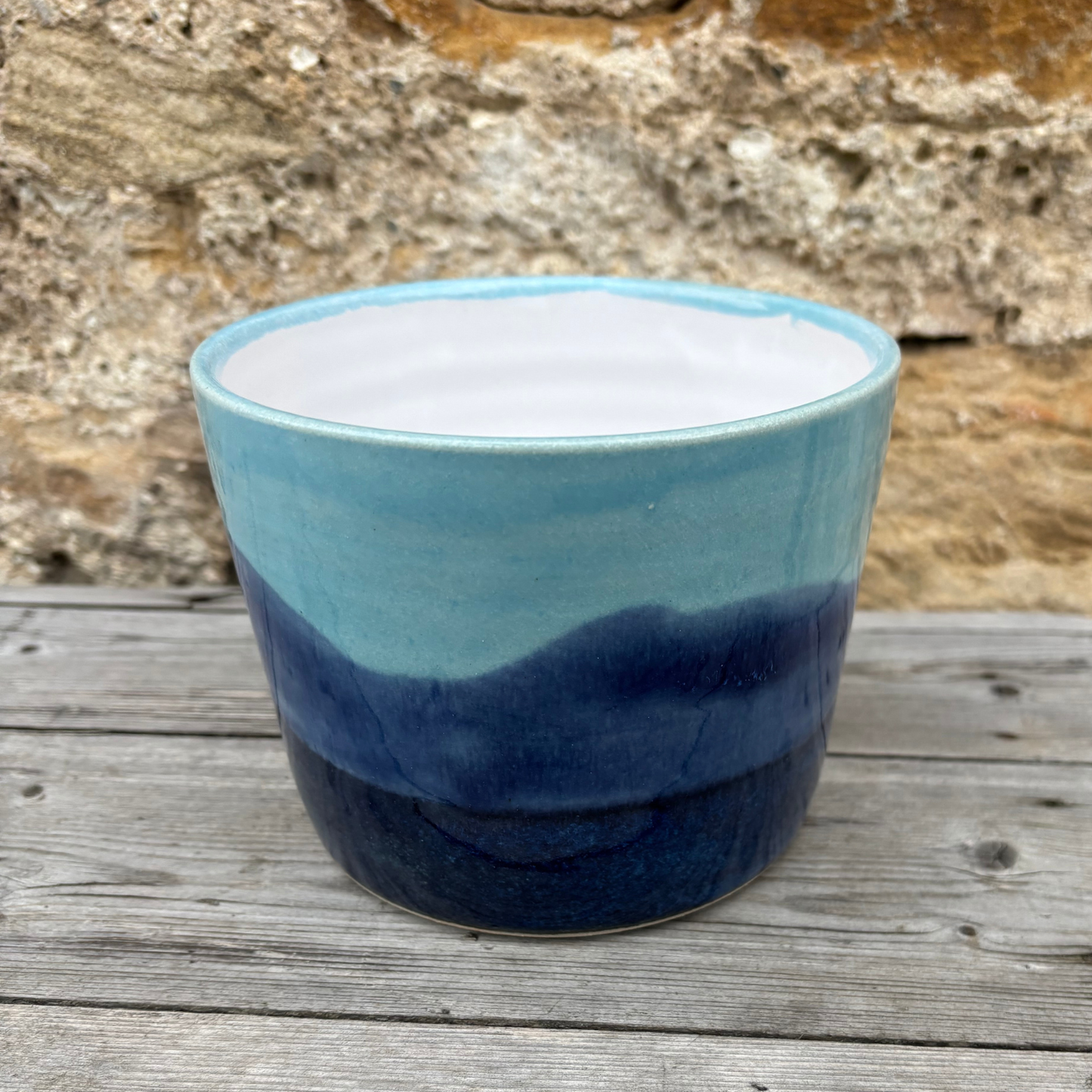 Ceramic planter with blue gradient on a wooden surface