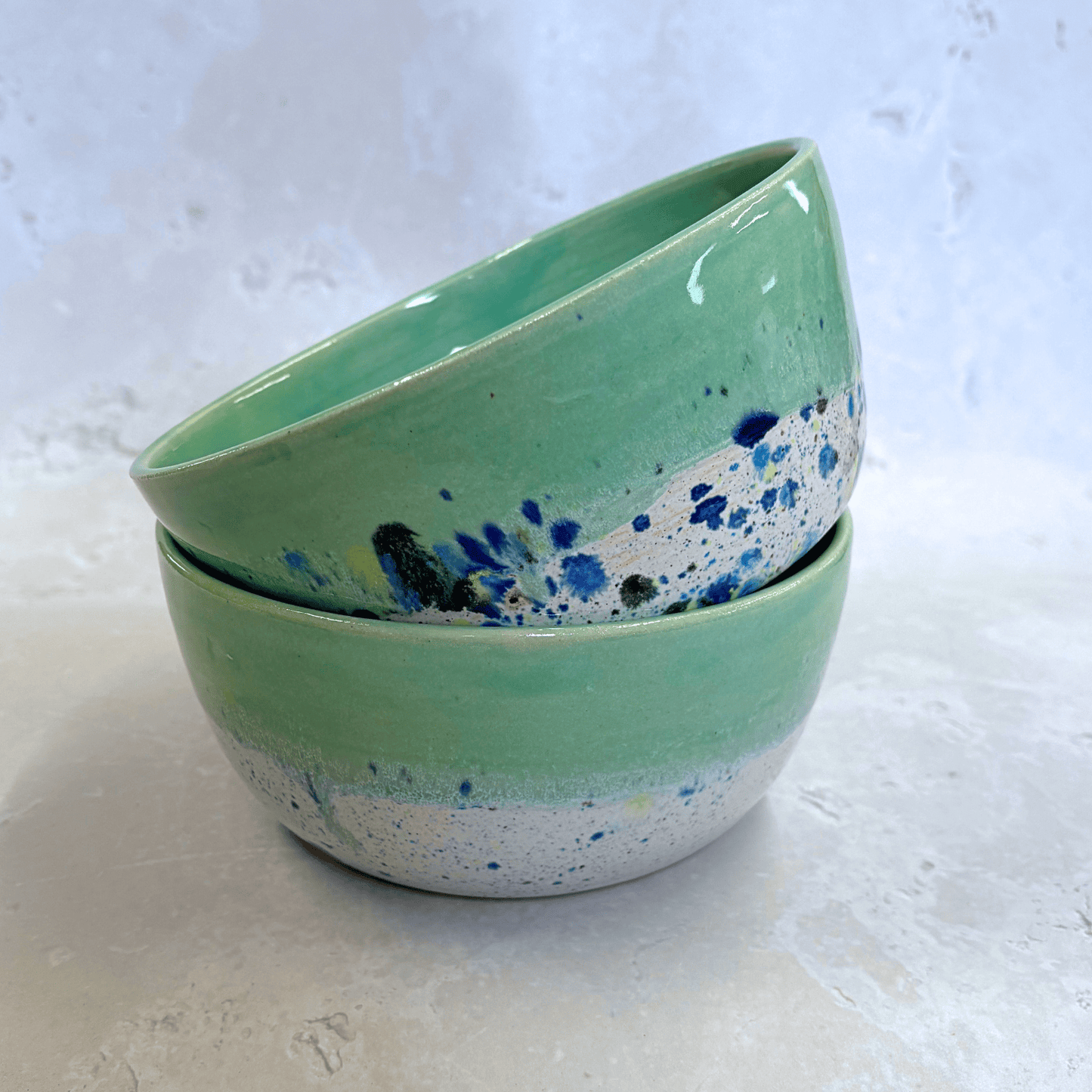 Ella Fletcher Designs Handmade Ramen Bowls in Green Shoreline, bowls stacked with solid green melting into multi-coloured speckles on a white background