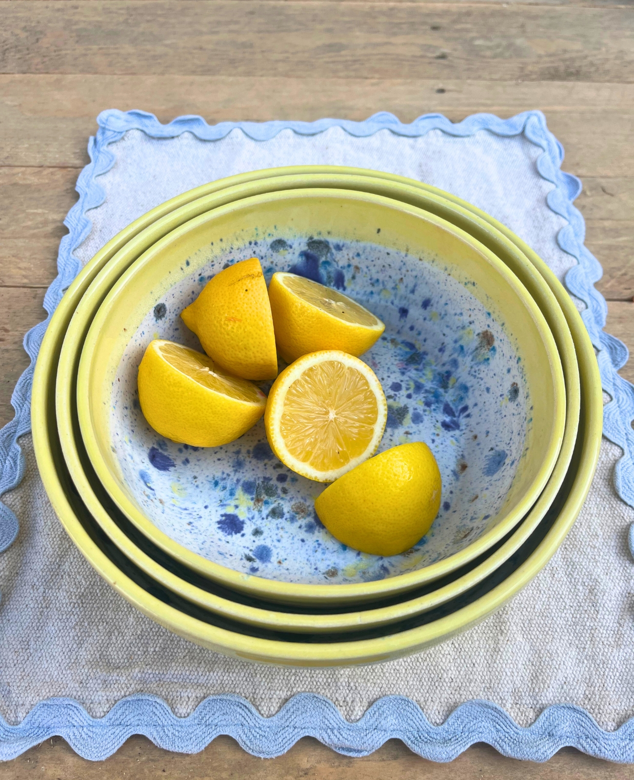 Stack of yellow ceramic bowls with lemons on a textured surface