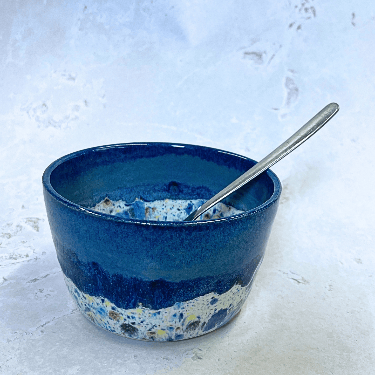 Ella Fletcher Designs Handmade Ceramic Small Bowl in Navy Shoreline design, round navy bowl with multicolour speckles, featured with spoon for scale