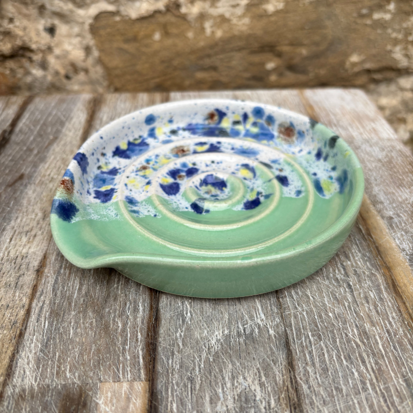 Green ceramic dish with speckled design on a wooden surface