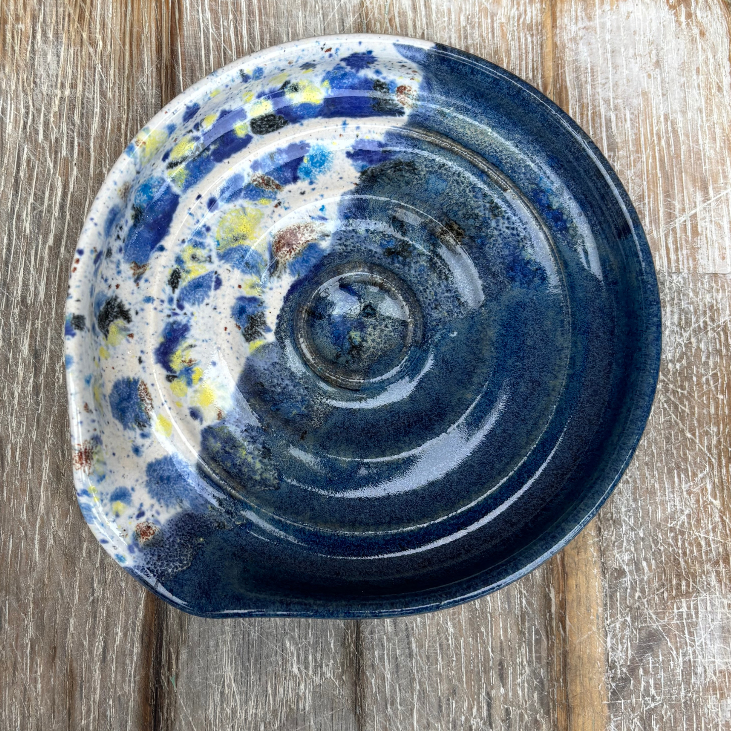 Ceramic dish with blue and white speckled design on a wooden surface