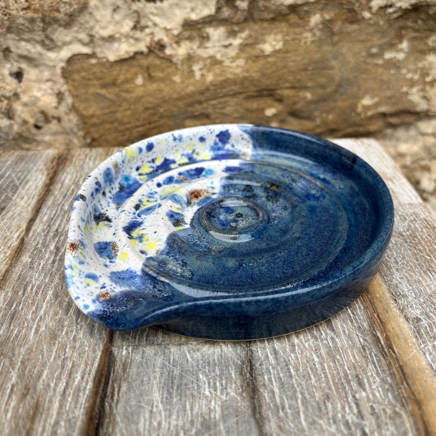 Blue ceramic dish with speckled pattern on a wooden surface
