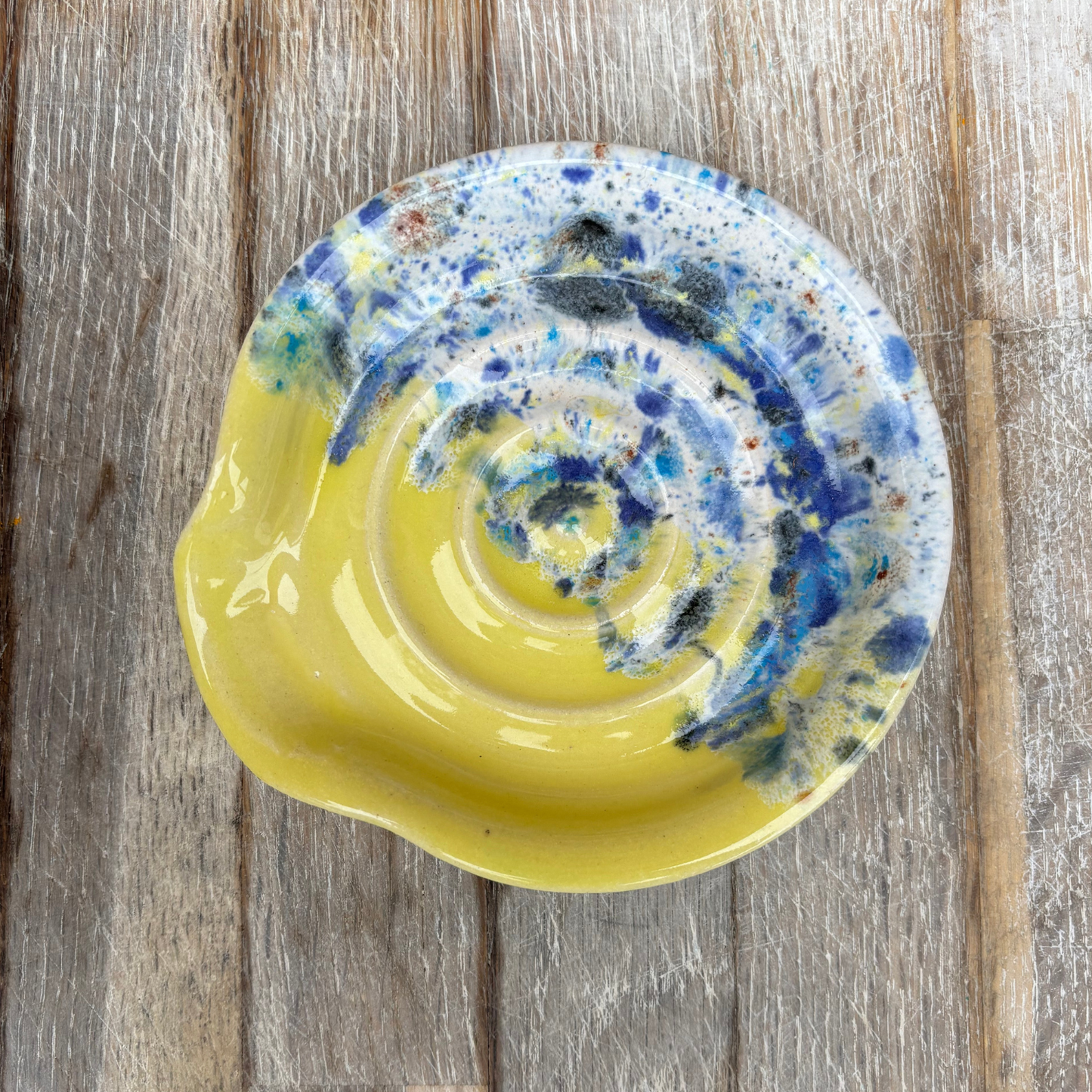 Yellow ceramic plate with blue and white abstract design on a wooden surface
