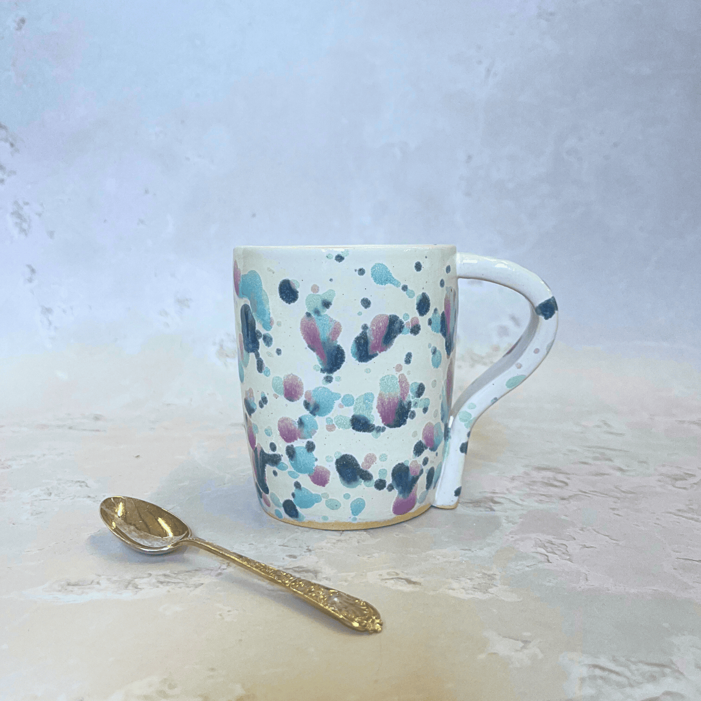Ella Fletcher Designs Handmade Pottery Standard Mug in Sweetpea Design, white background with specks of blues, pinks and purples inspired by sweet pea flowers