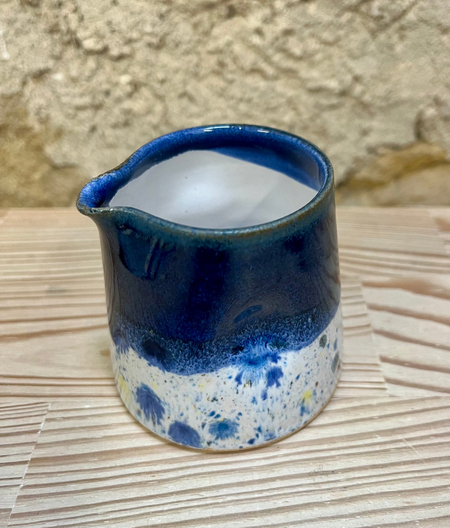Ceramic pitcher with blue and white speckled design on a woven mat