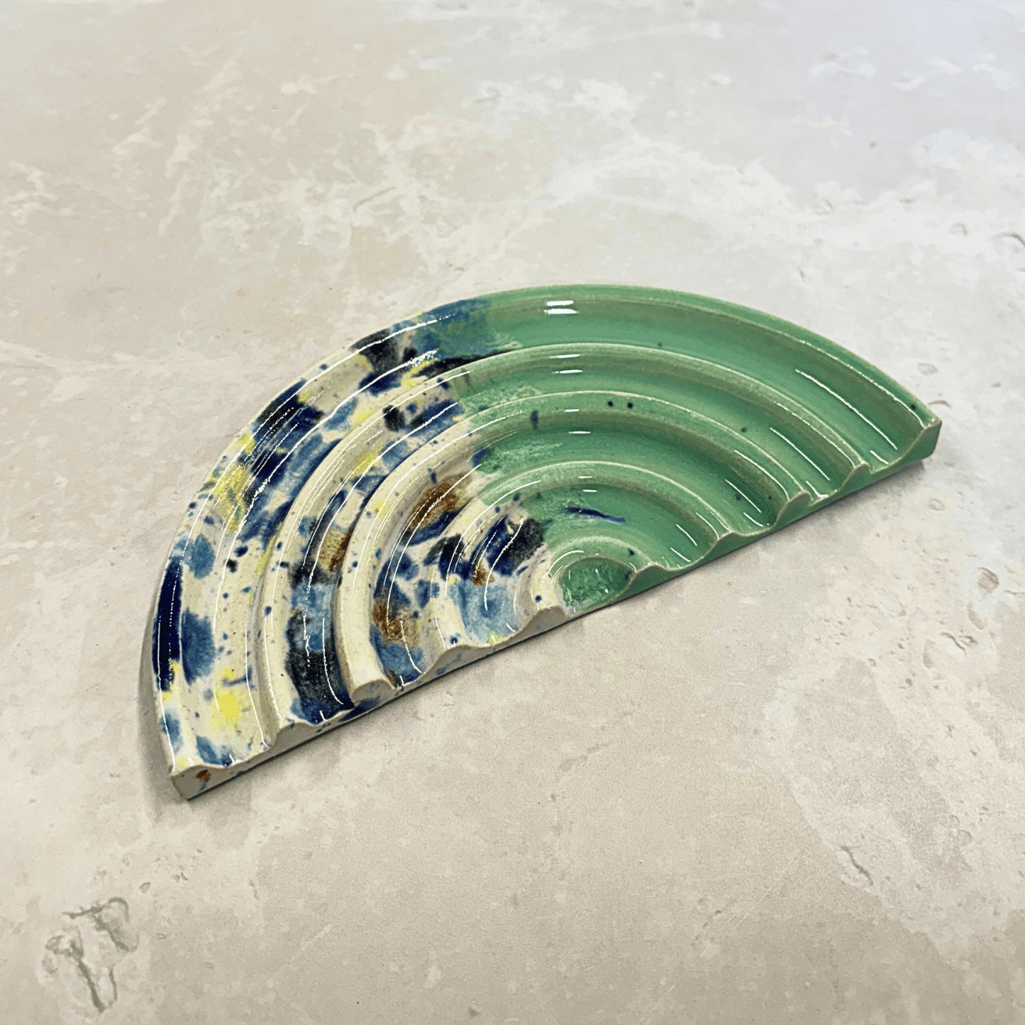 Ella Fletcher Designs Handmade Ceramic UK Soap Dish in Green Shoreline design, semi-circle with grooved edges, half pale green and half multi-coloured speckles