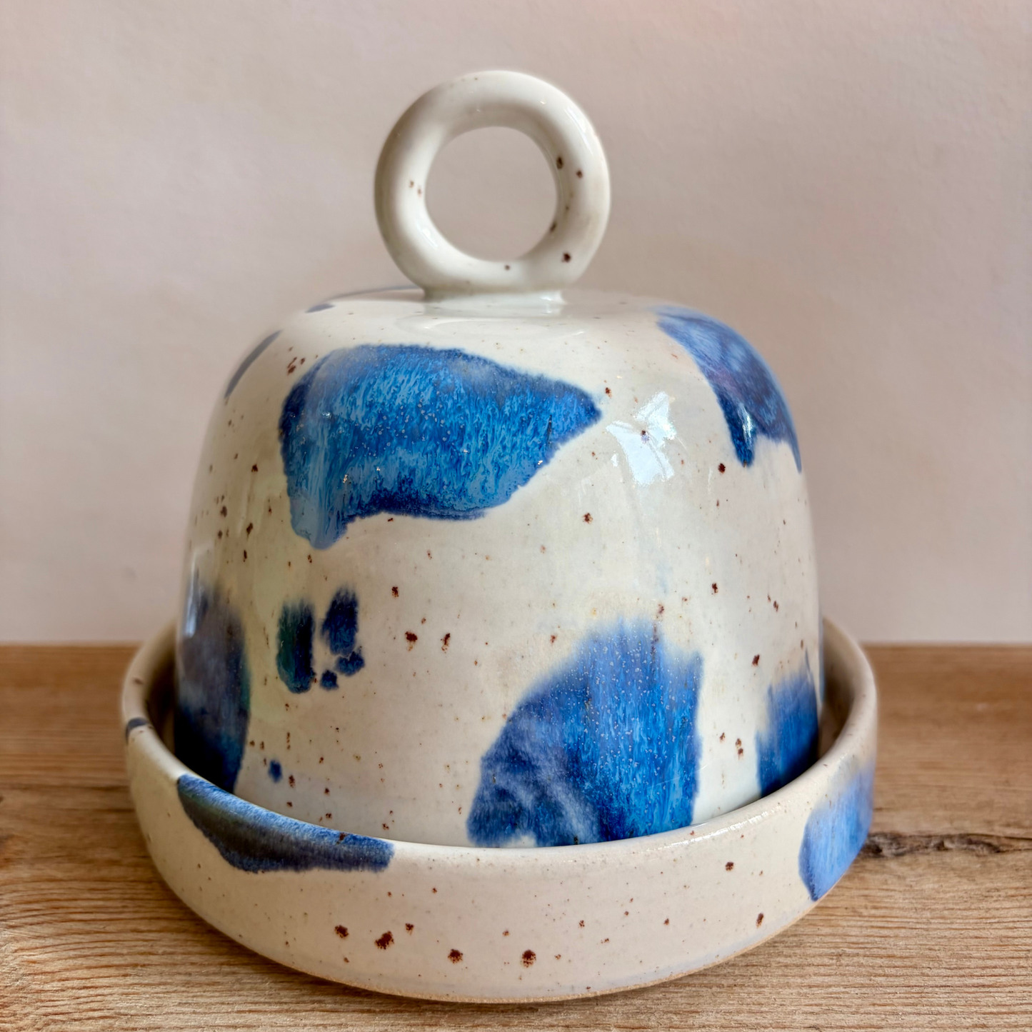 Ceramic butterdish with blue speckled design on a wooden surface