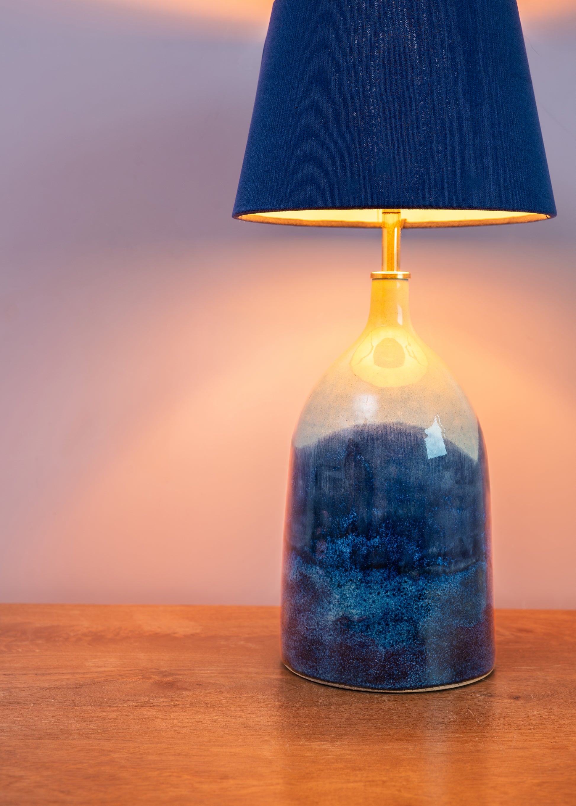 Table lamp with blue textured base and dark blue shade on a wooden surface.
