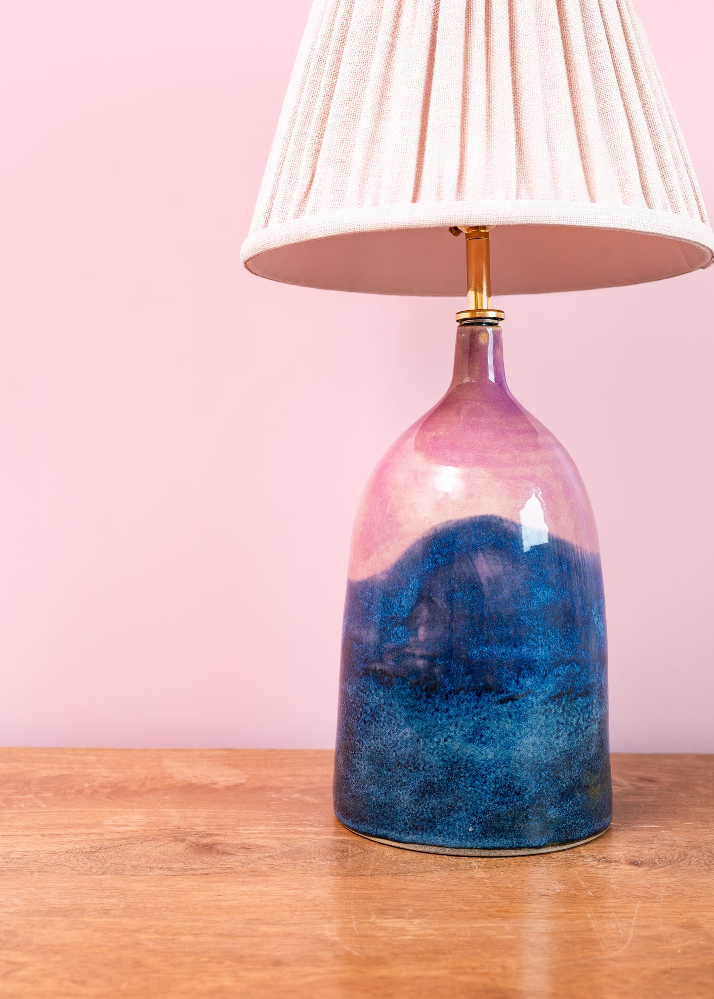 Table lamp with a unique blue and pink design on a wooden surface with a pink background