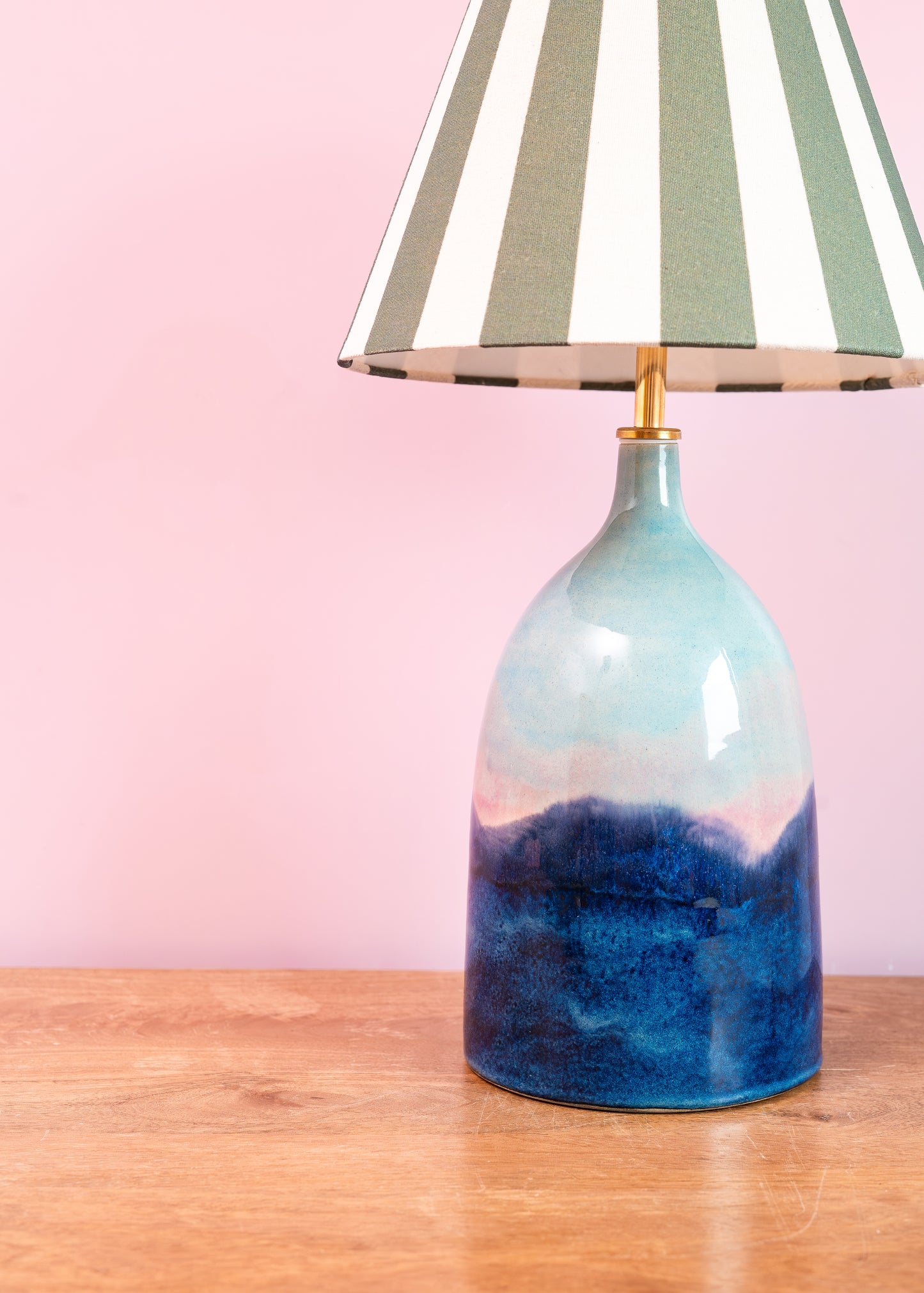 Table lamp with a blue and pink gradient base on a wooden surface with a pink background
