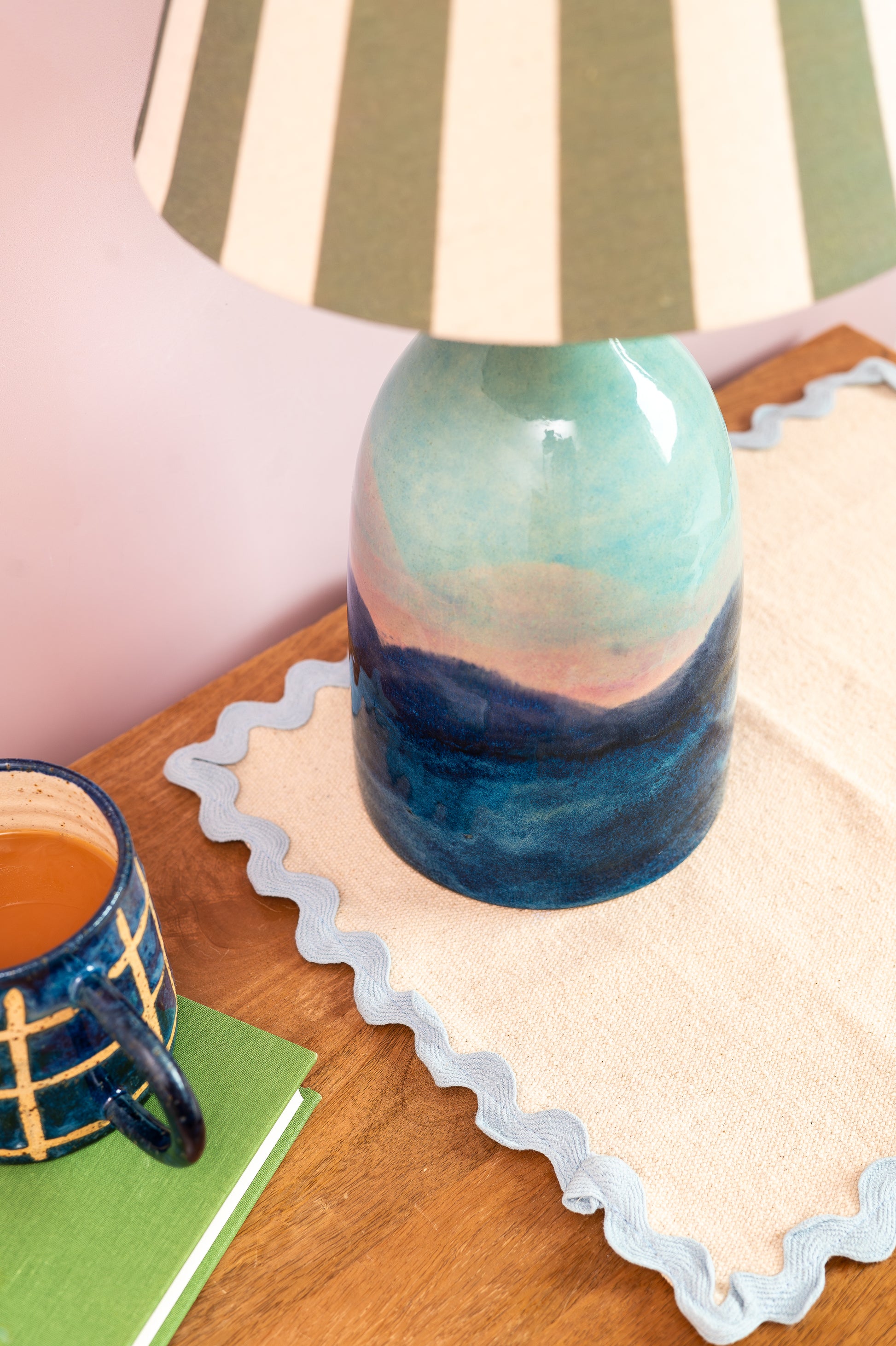 Colorful glass bottle used as a lamp on a wooden surface with a mug and notebook.