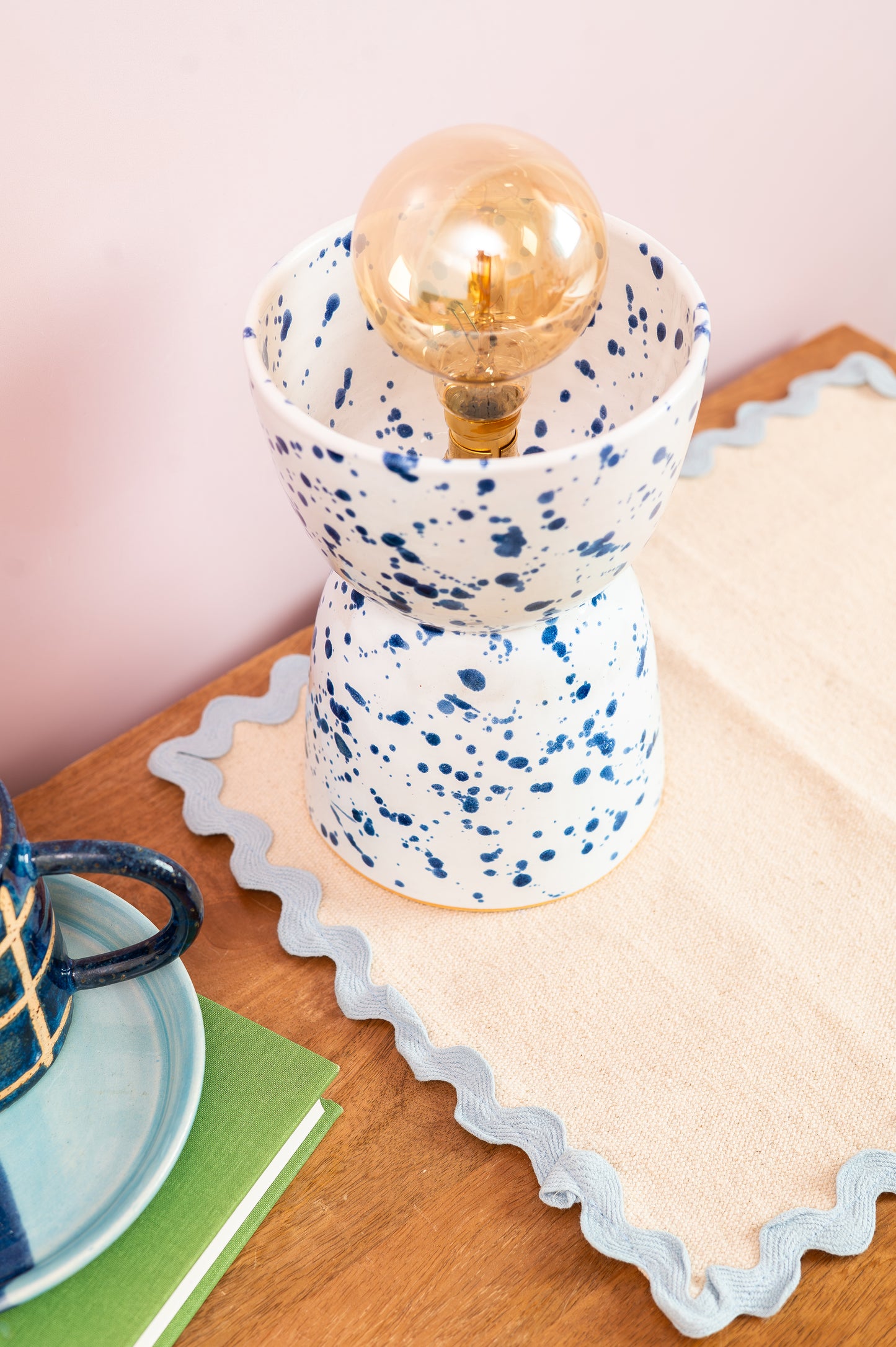 Speckled ceramic lamp with a vintage-style light bulb on a wooden surface.