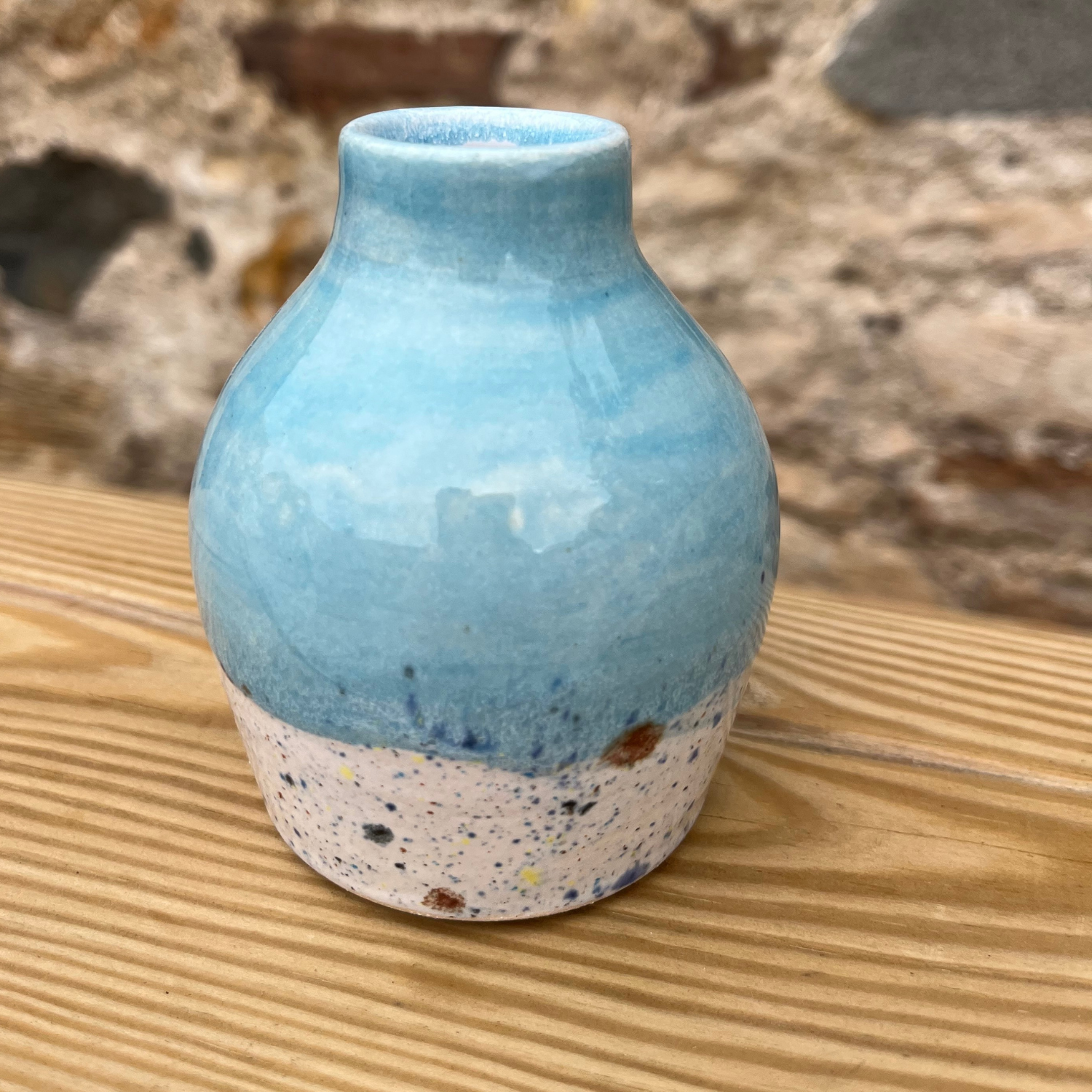 Blue ceramic vase with speckled base on a wooden surface