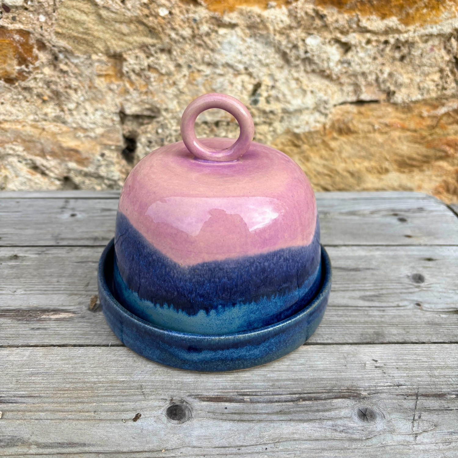 Ceramic butter dish with pink and blue gradient on a wooden surface