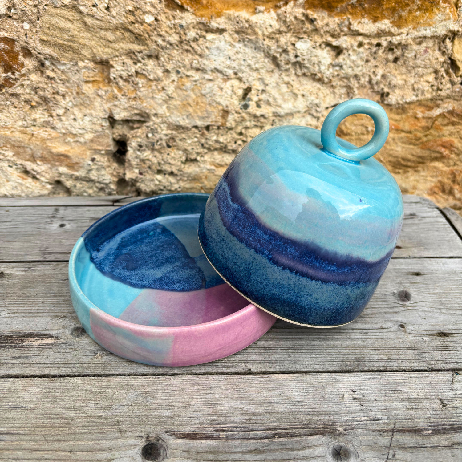Ceramic jar with a lid featuring blue and pink gradient on a wooden surface.