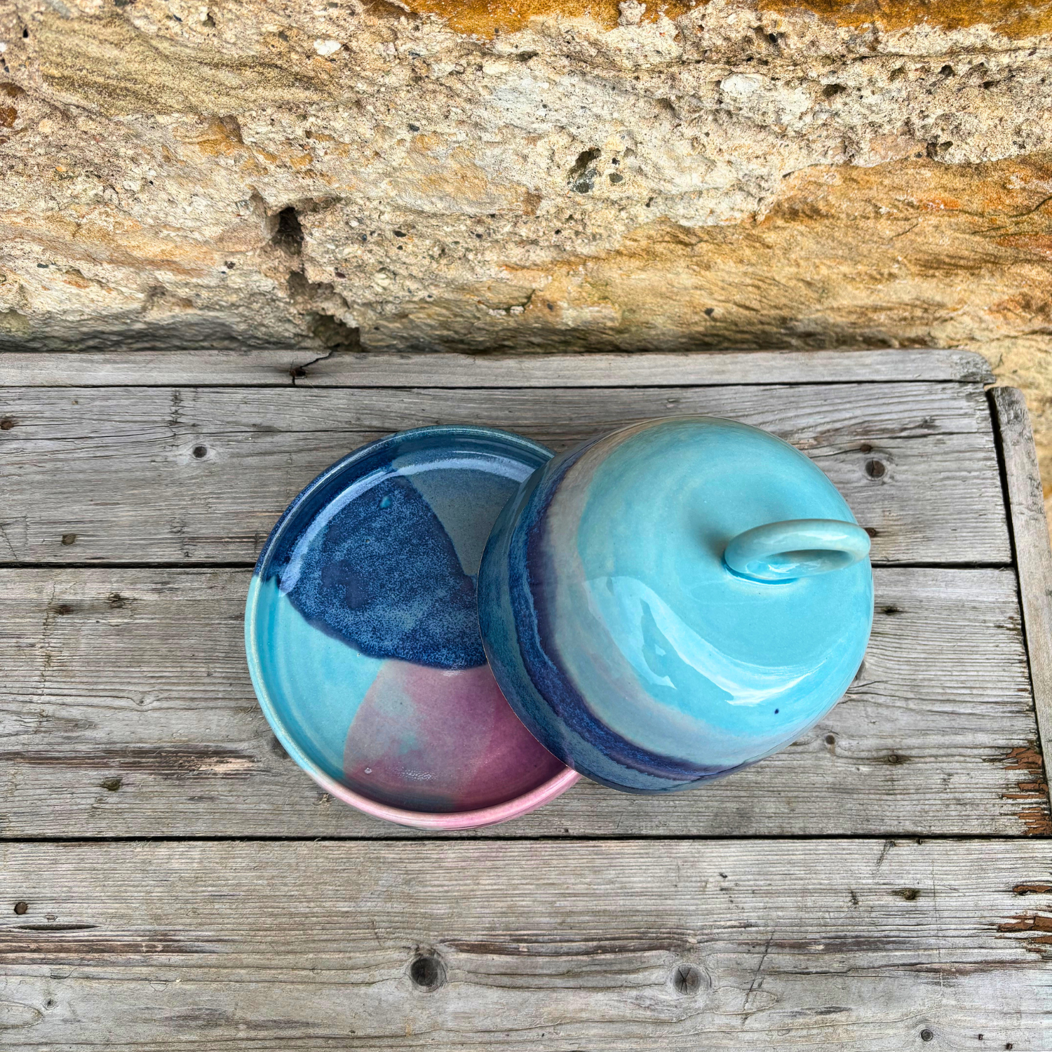 Ceramic butter dish with blue and pink marbled design on a wooden surface.