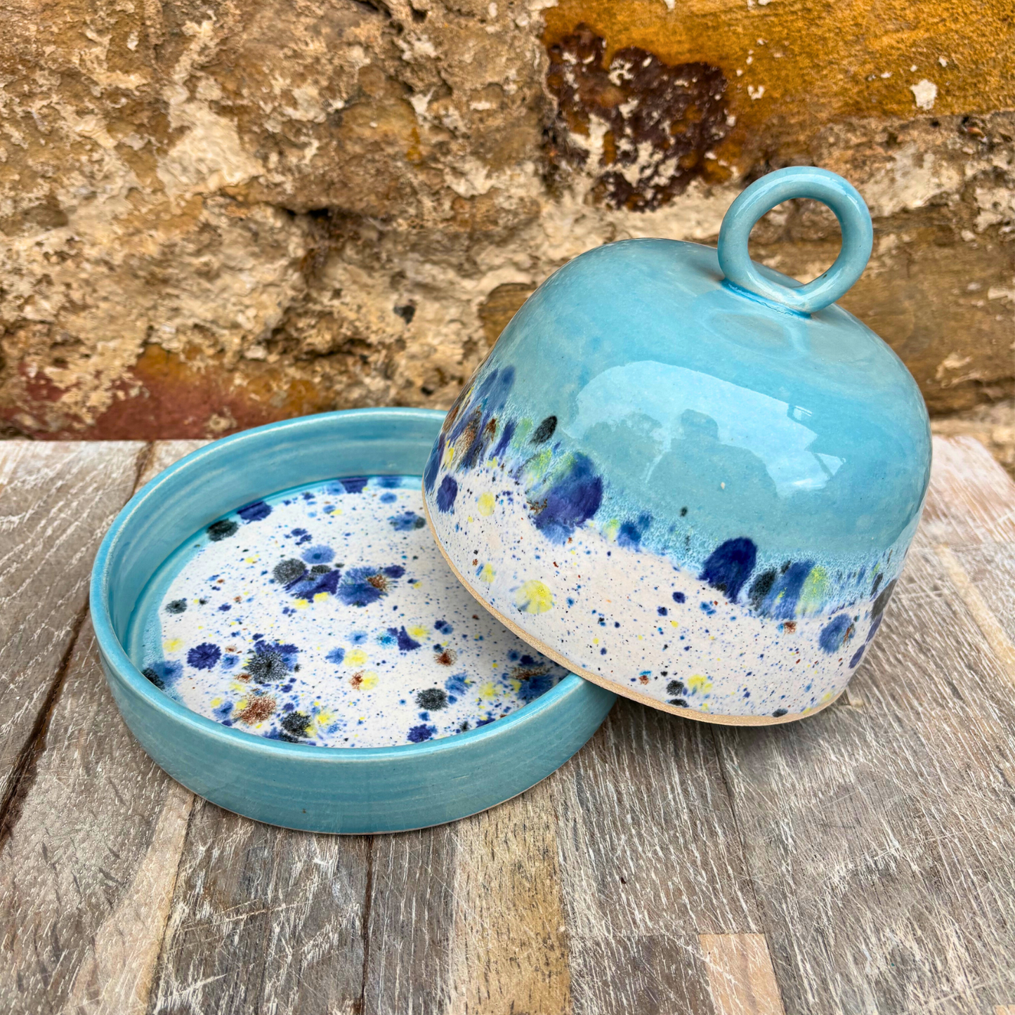 Blue ceramic container with speckled design on a wooden surface