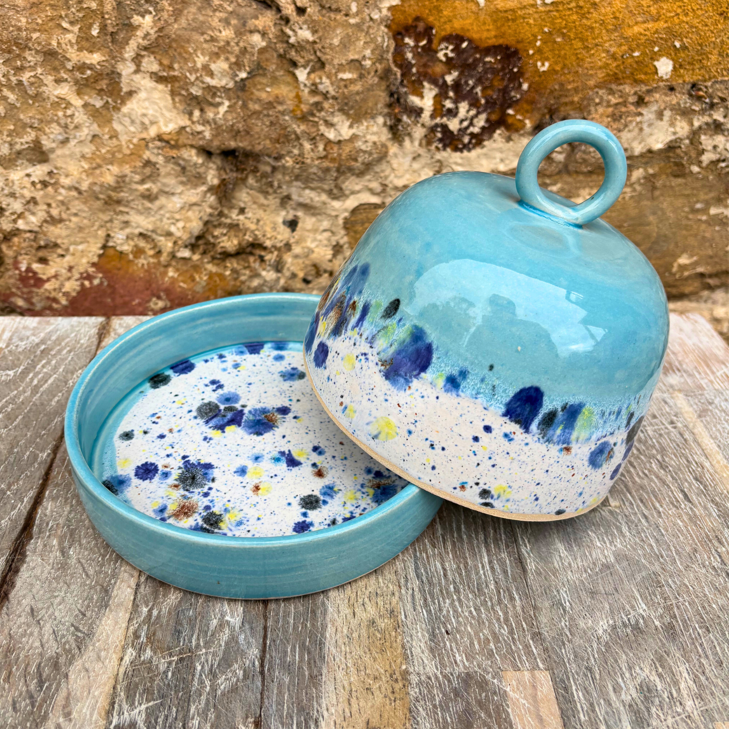 Blue ceramic container with speckled design on a wooden surface