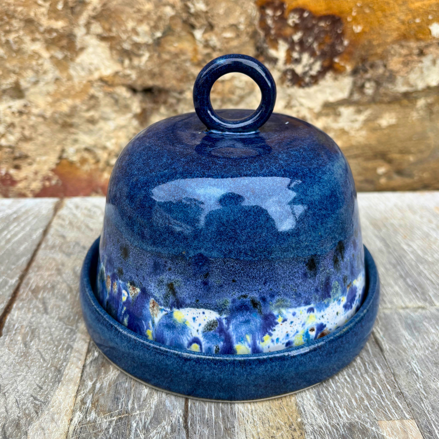 Blue ceramic cheese dome with a textured surface on a wooden surface