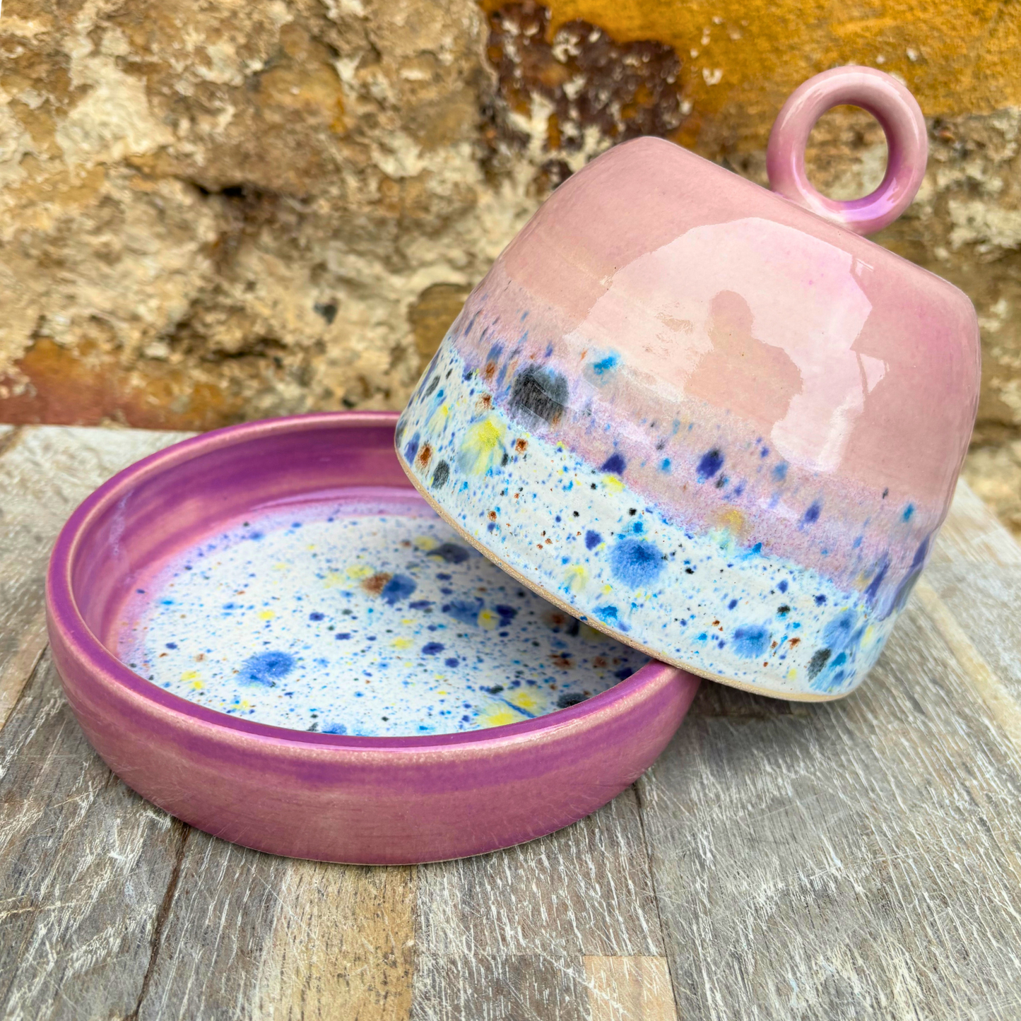Pink ceramic container with speckled interior on a wooden surface