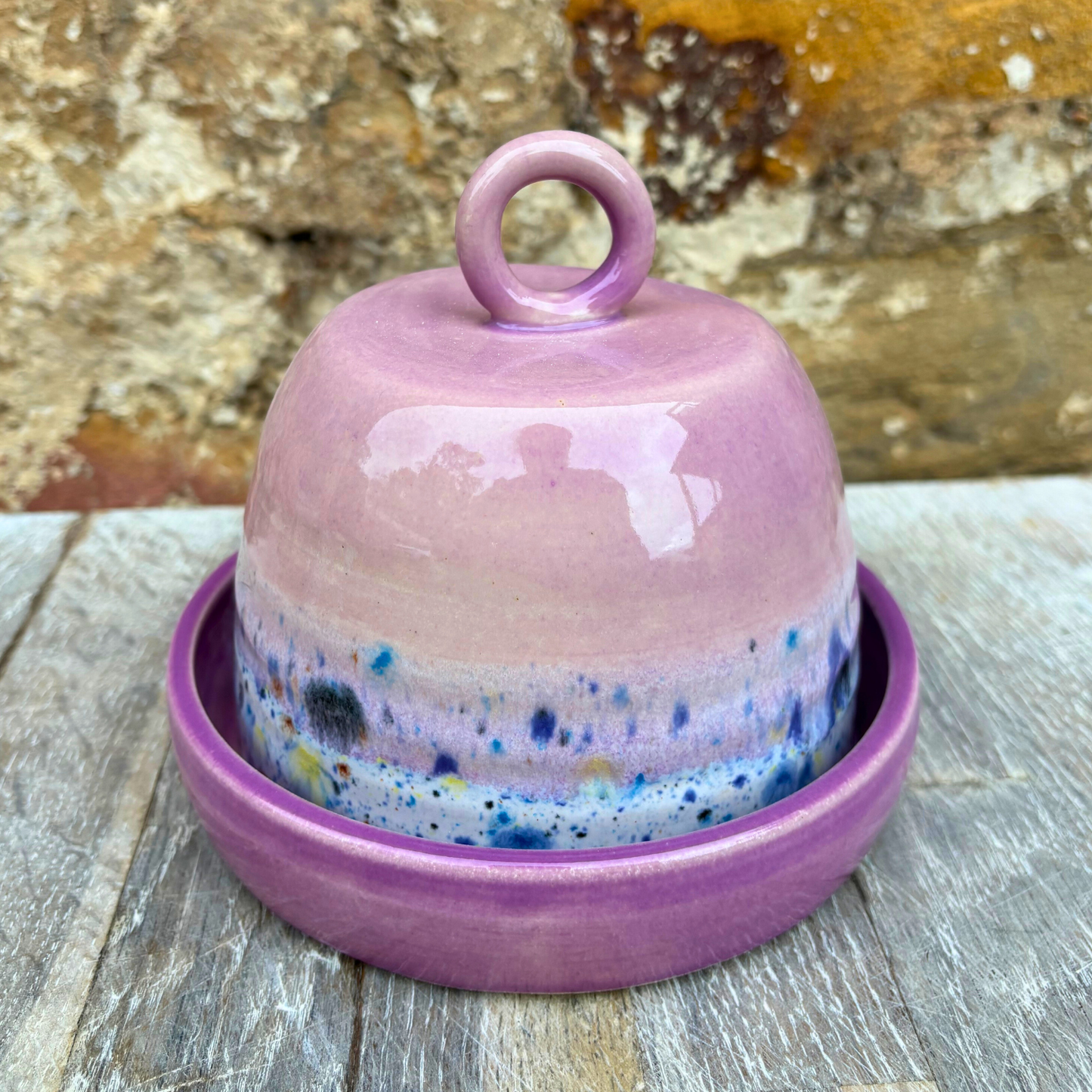 Pink ceramic bell with speckled design on a wooden surface