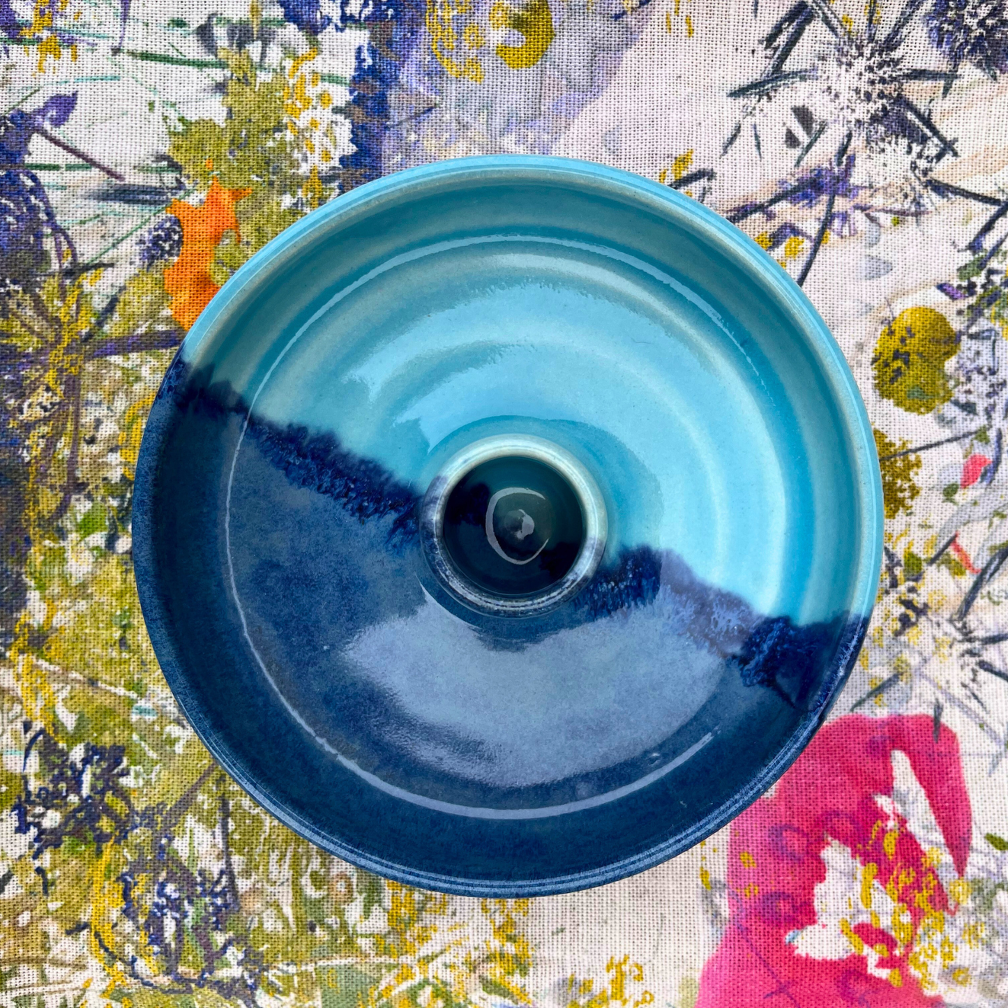 Blue ceramic bowl on a colorful floral fabric background