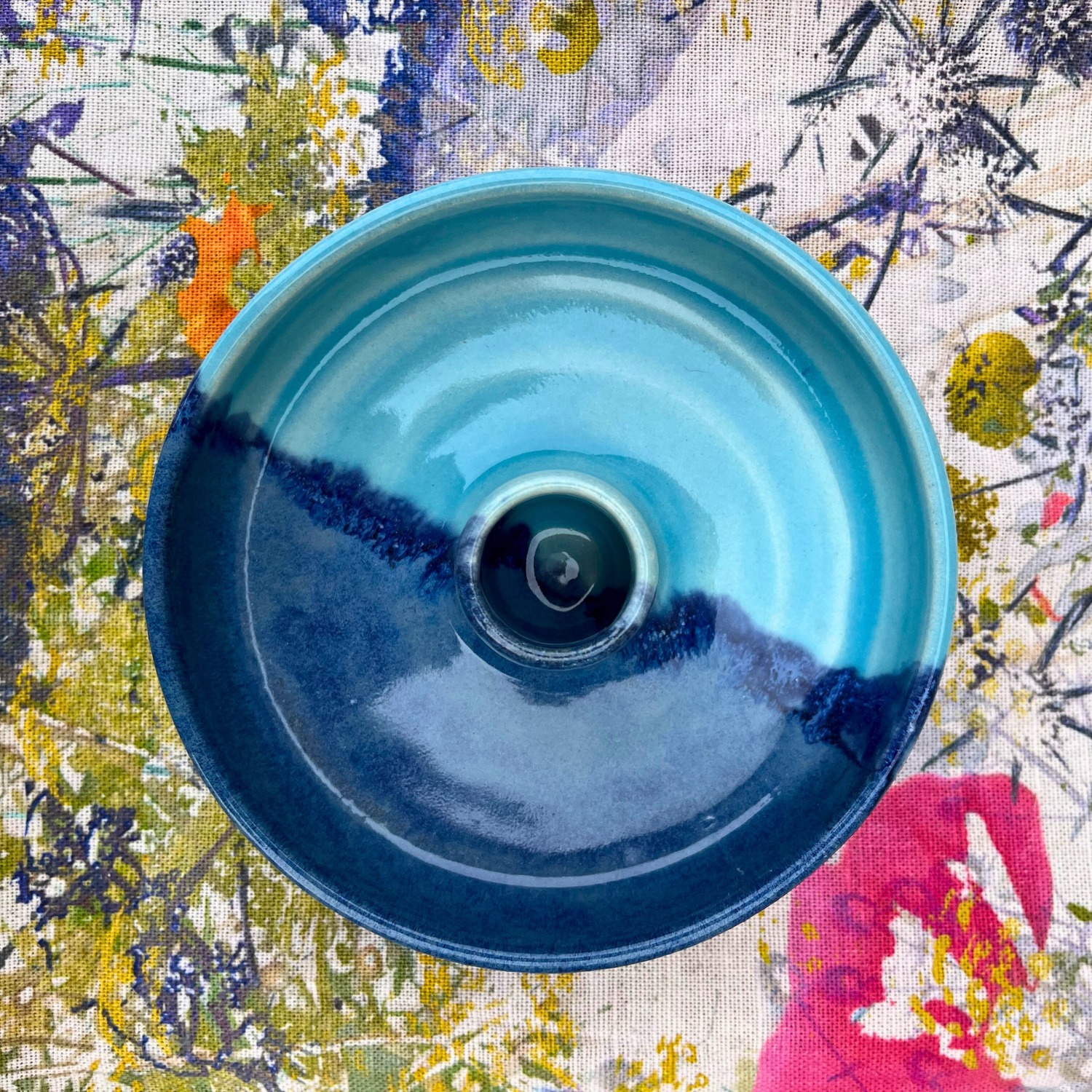 Blue ceramic bowl on a colorful floral fabric background