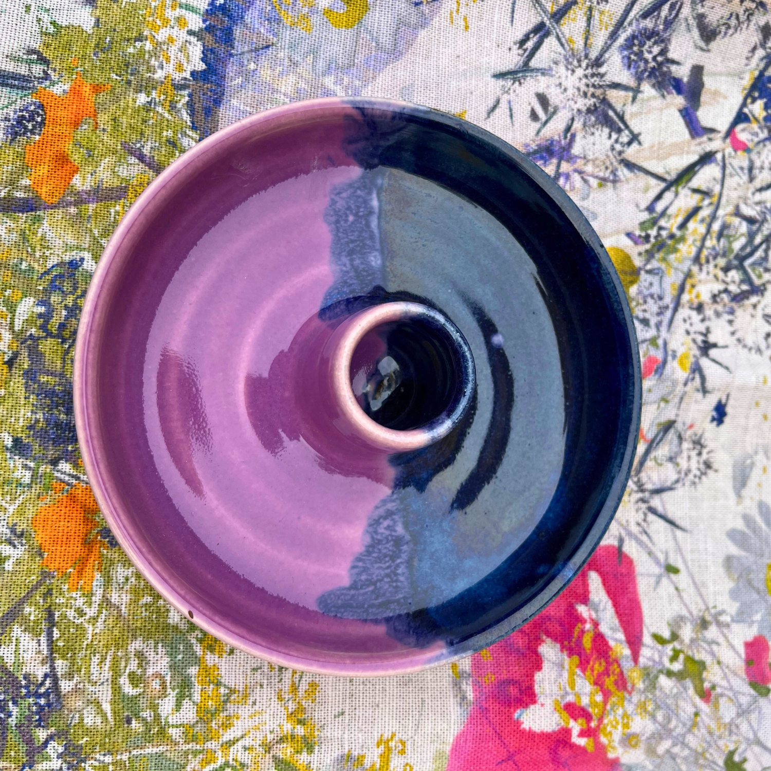 Purple and blue ceramic bowl on a colorful floral fabric background