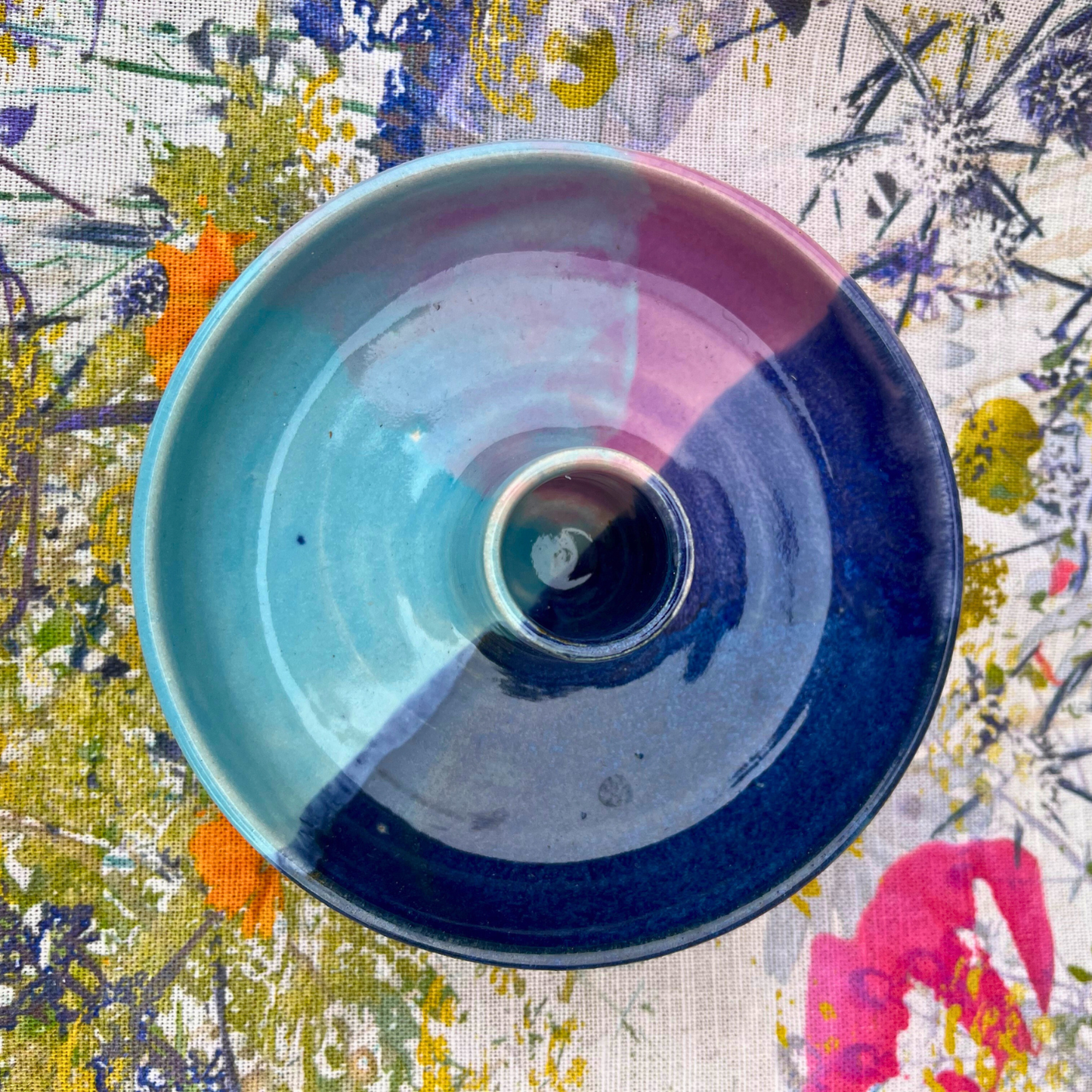 Ceramic bowl with blue and pink gradient on a colorful floral fabric background