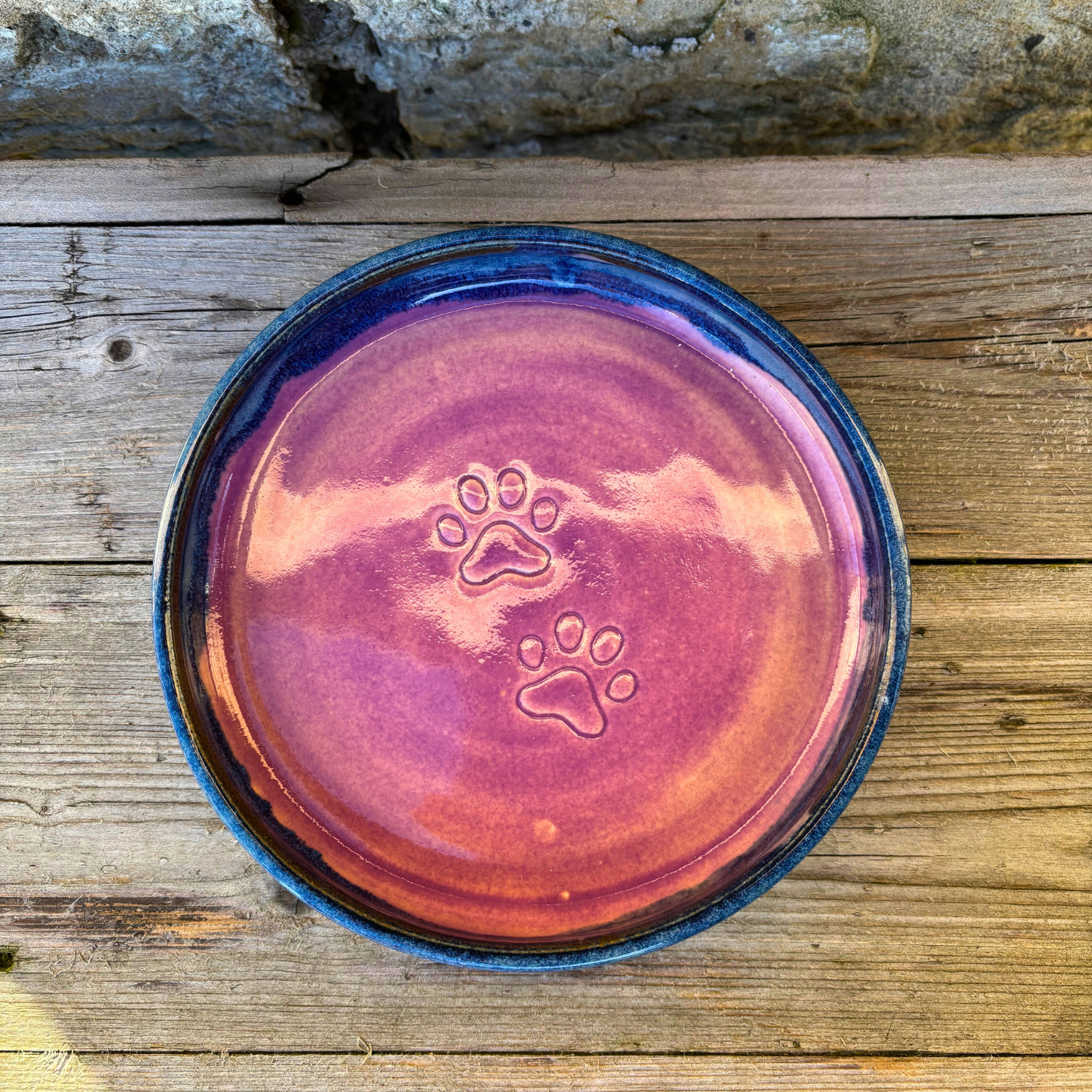 Ceramic dish with paw prints on a wooden surface