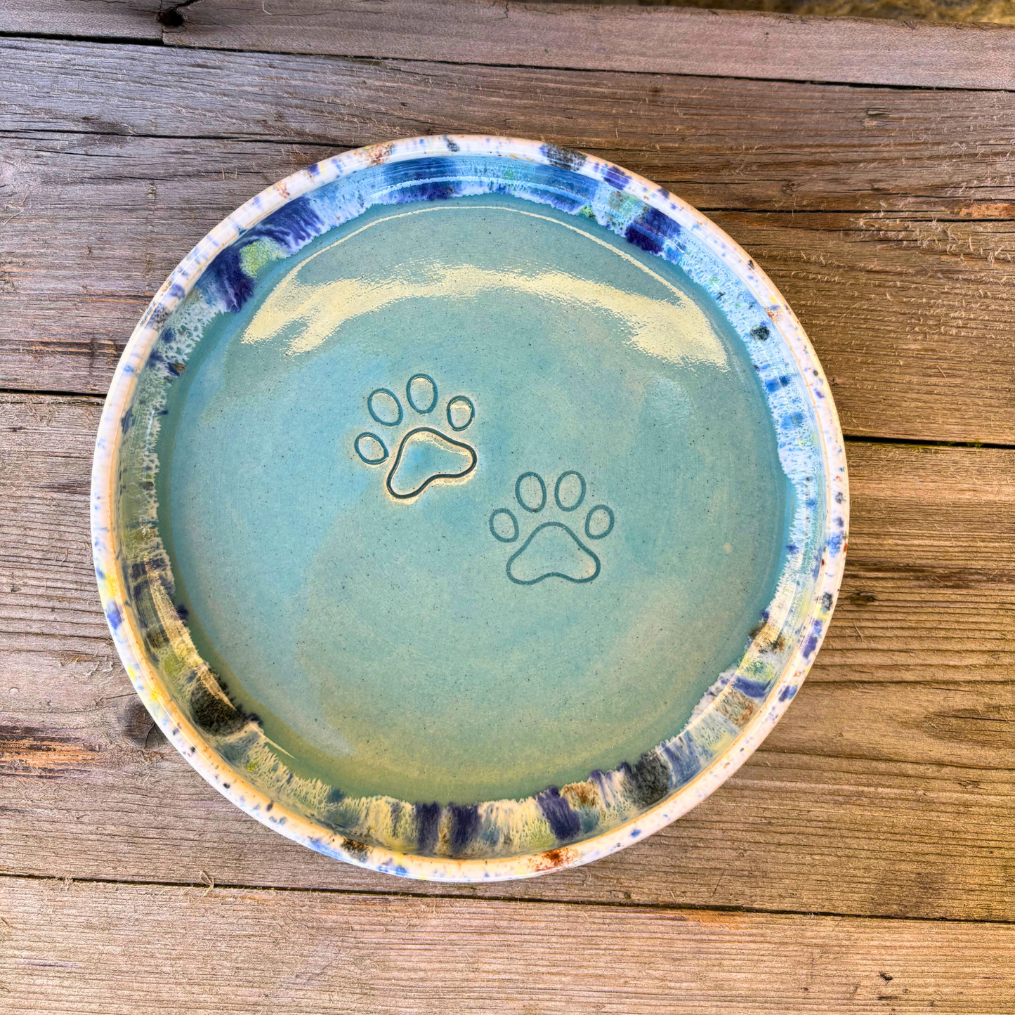 Ceramic bowl with paw prints on a wooden surface
