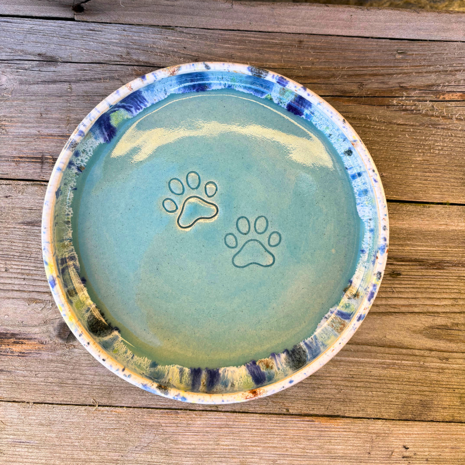 Ceramic bowl with paw prints on a wooden surface