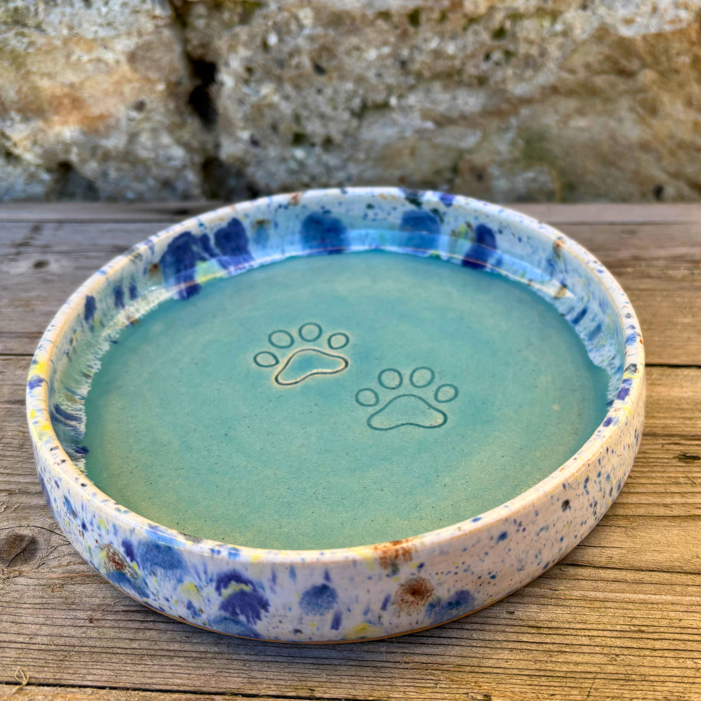Ceramic pet bowl with paw prints on a wooden surface