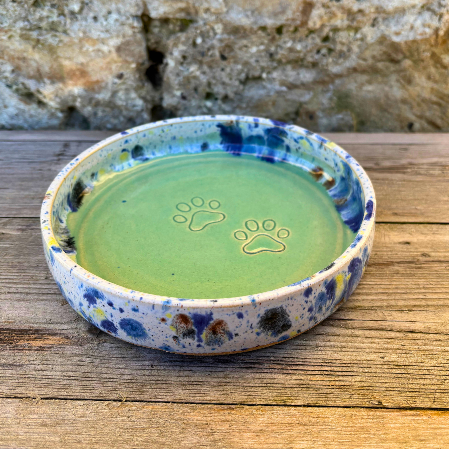 Ceramic dish with paw prints on a wooden surface
